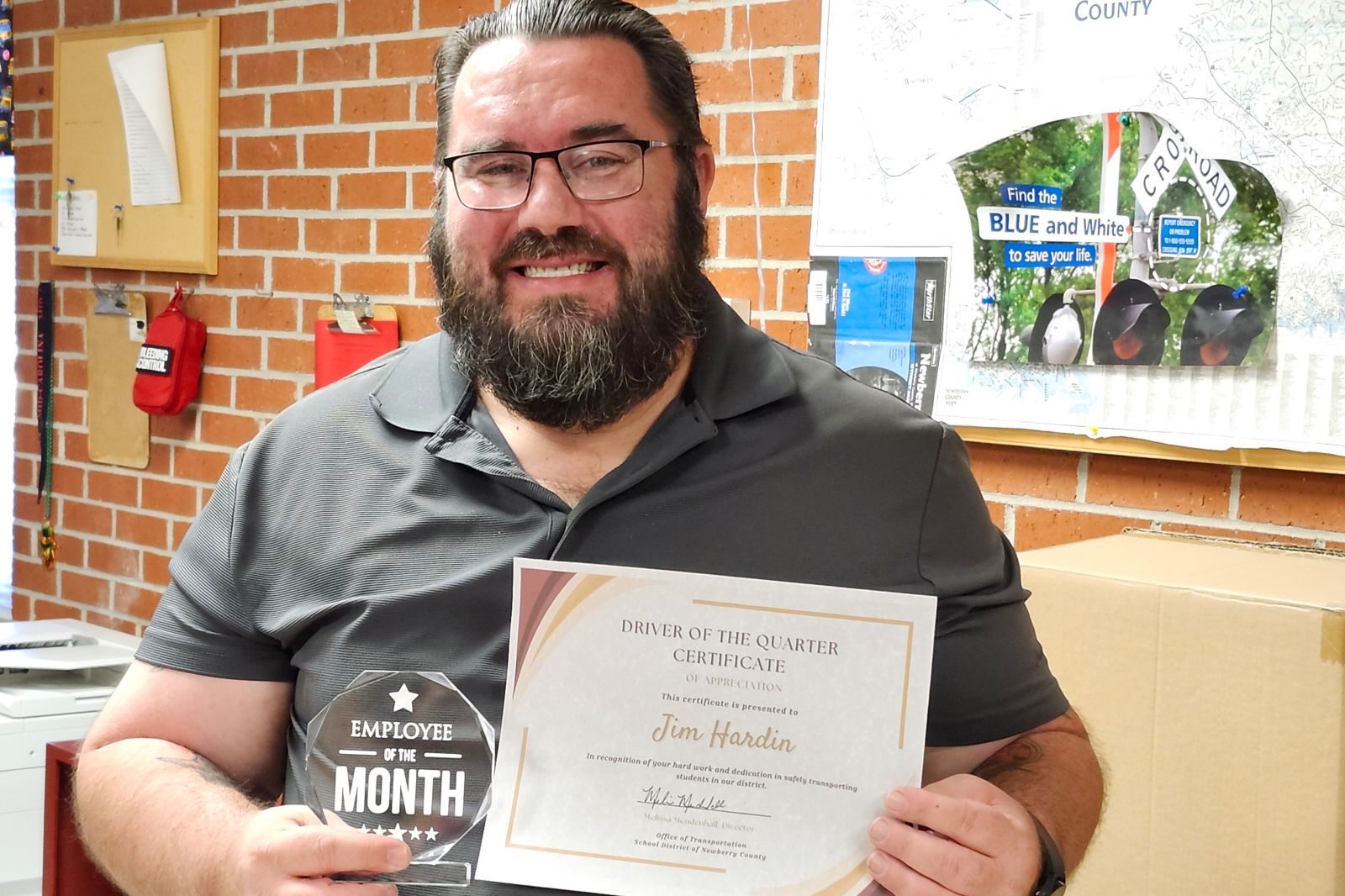 Jim Hardin holding an "Employee of the Month" award and a certificate.