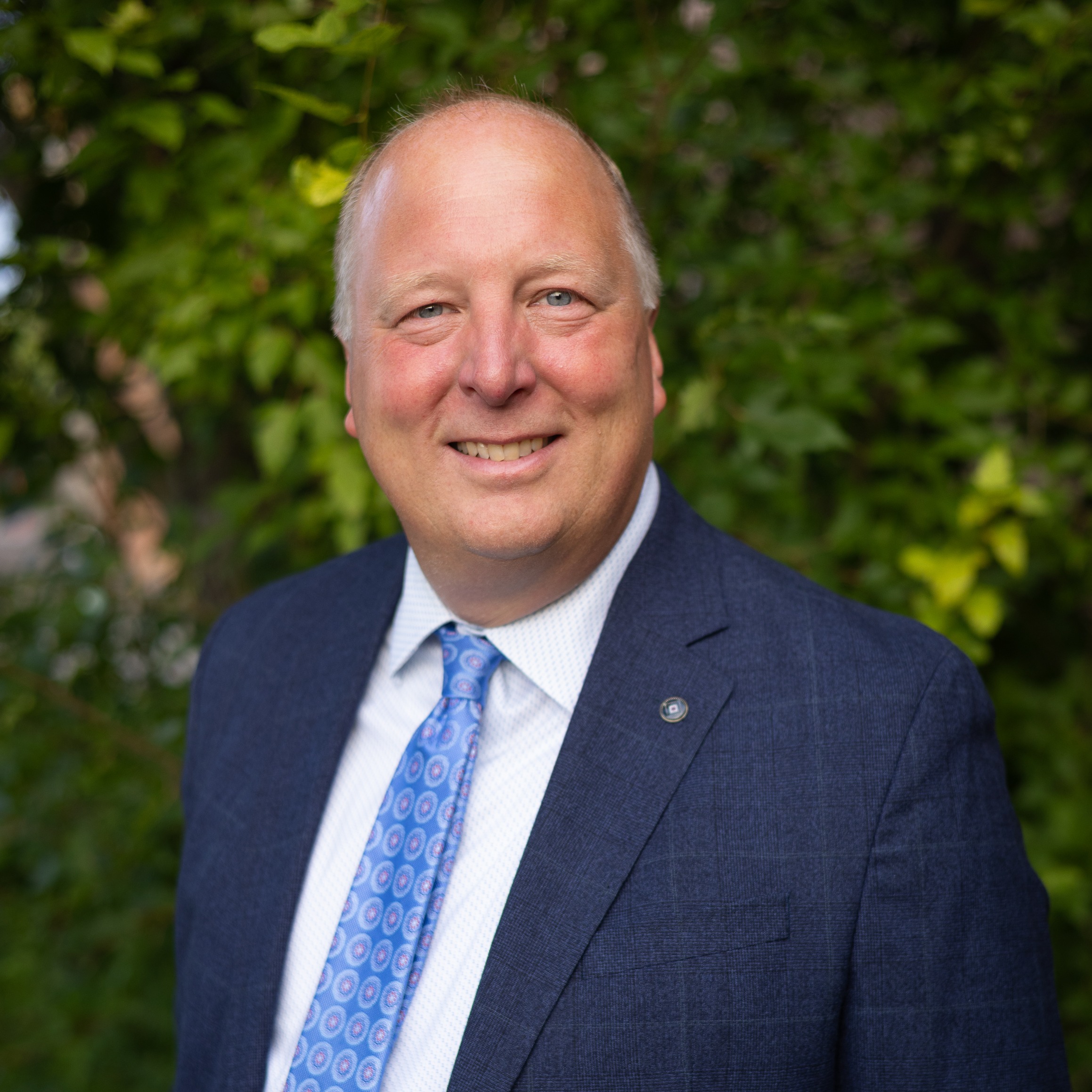 Smiling man blue blazer and tie standing outside