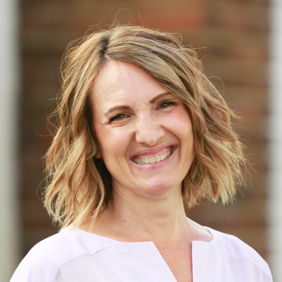 Smiling woman with white shirt and should length blonde hair.