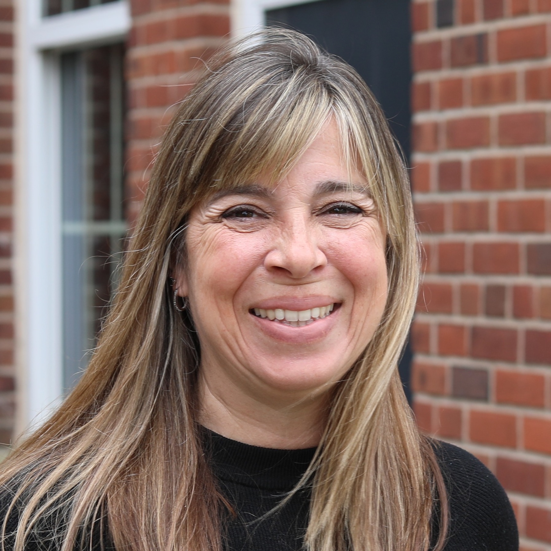 Jessica Nightingale smiles for a photo, standing outside in front of a brick building.