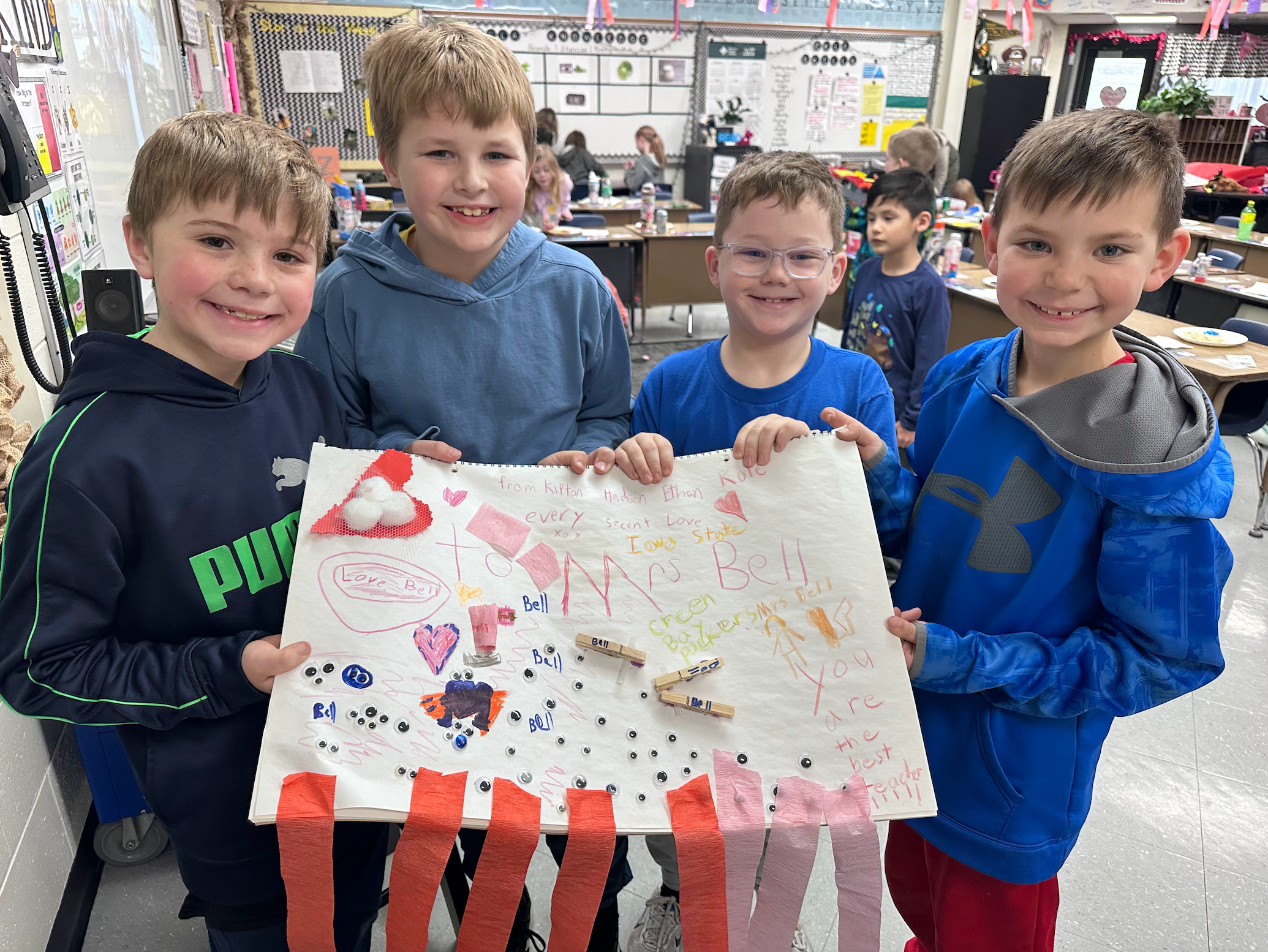 Four students holding up a poster about their teacher and why she is the best