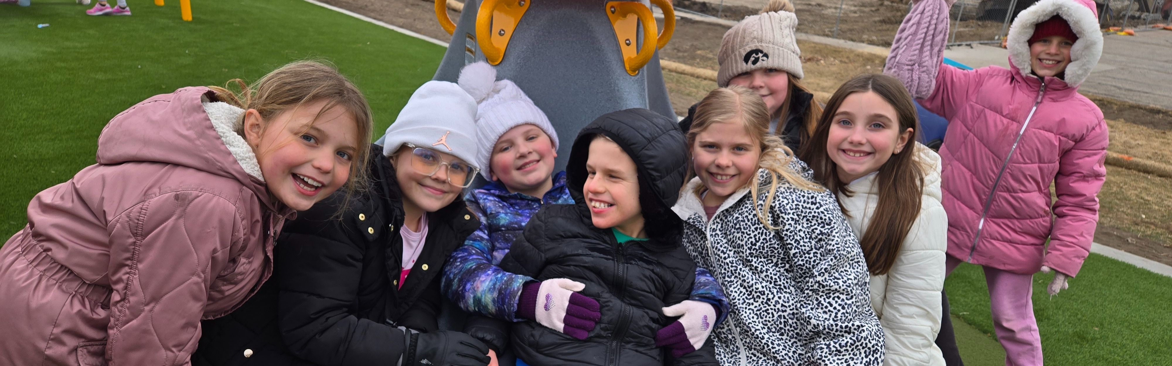 Students playing on a merry go round swing on the playground