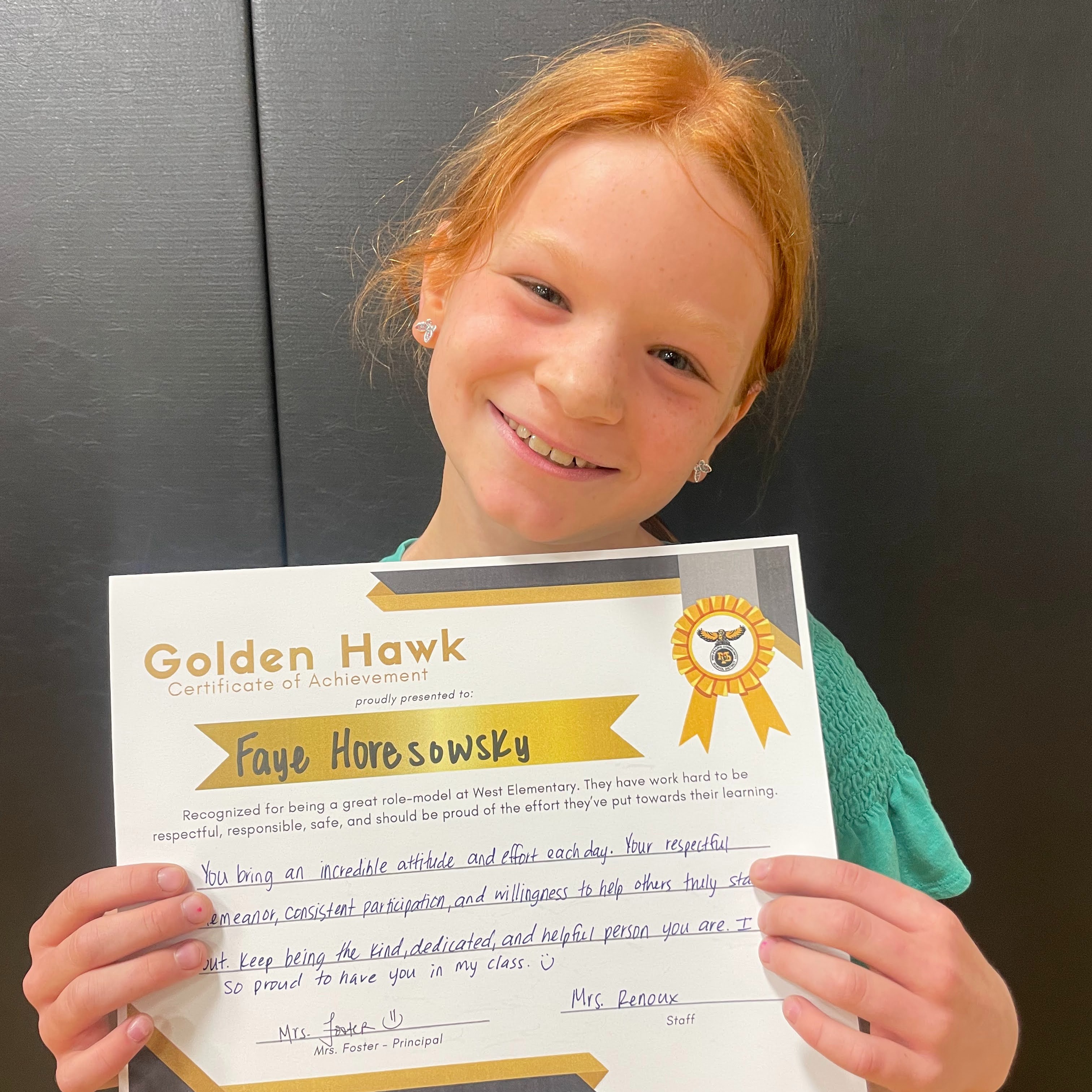 Student holding up her award certificate for positive behavior; Text on award reads: Golden Hawk Certificate of achievement Faye Horesowsky Recognized for being a great role-model at West Elementary. They hae worked hard to be respectful, responsible, safe, and should be proud of the effort they've put towards their learning. You bering an incredible attitude and effort each day. Your respectful demeanor, consistent participation, and willingness to help others truly stand out. Keep being the kind, dedicated, and helpful person you are. I am so proud to have you in my class. Mrs. Foster Mrs. Renous