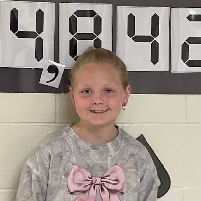 Reese - West Elementary Student; standing in front of a bulletin board that reads 14,842