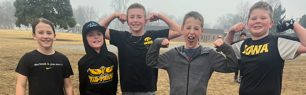 Group of students outside playing football in the field, one shirt text reads Mid-Prairie Golden Hawks, one shirt text reads IOWA