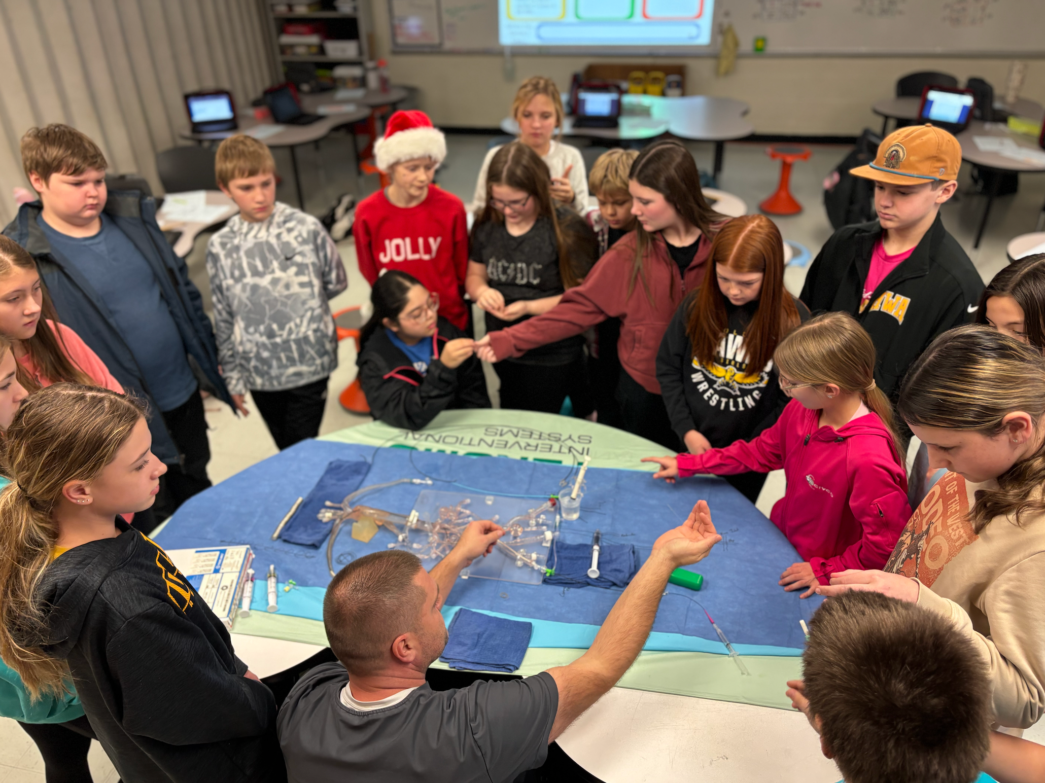 Students surrounding a table watching a science demonstration by a volunteer