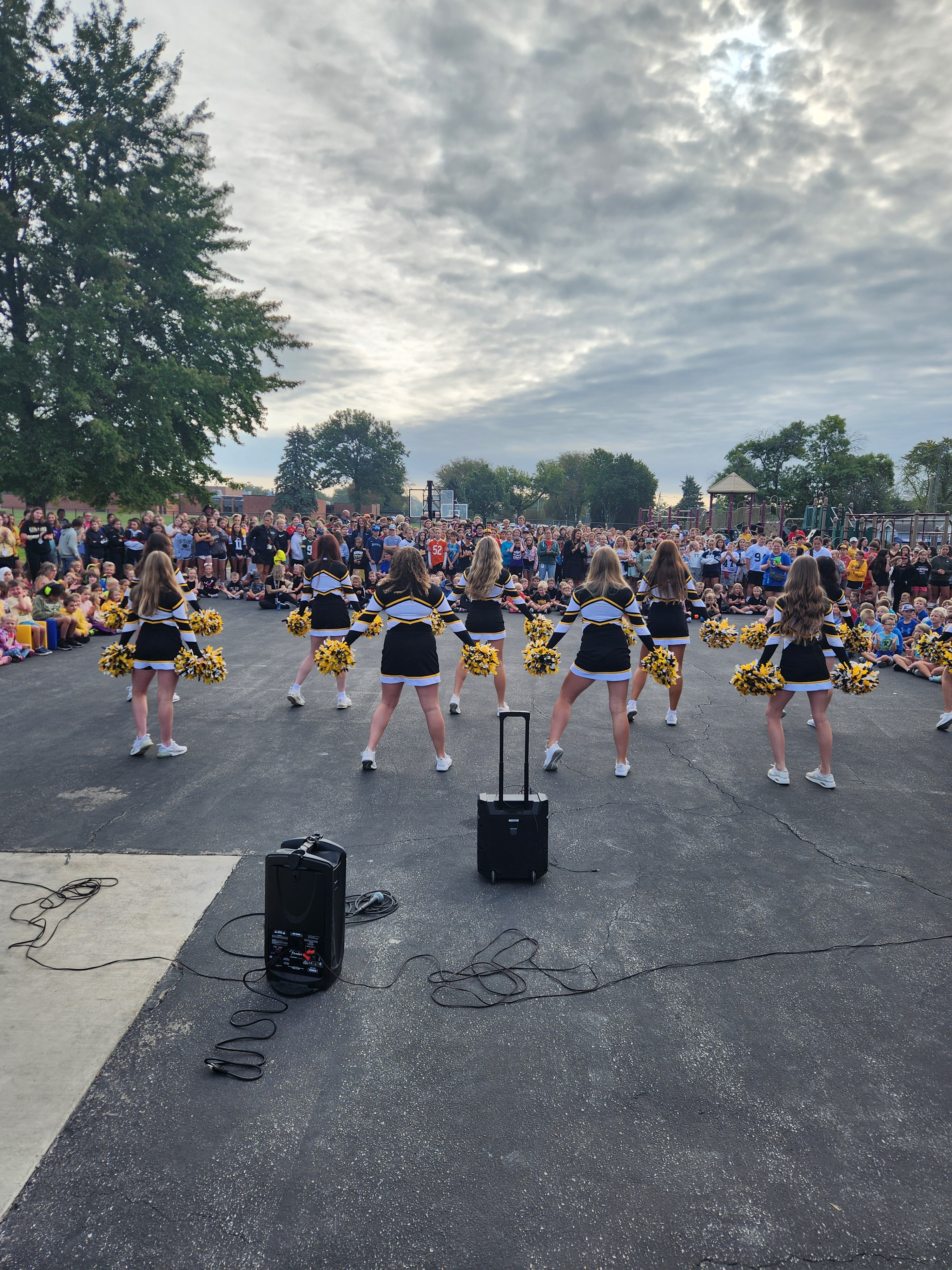 high school dance team performing for elementary and middle school students out on the playground blacktop