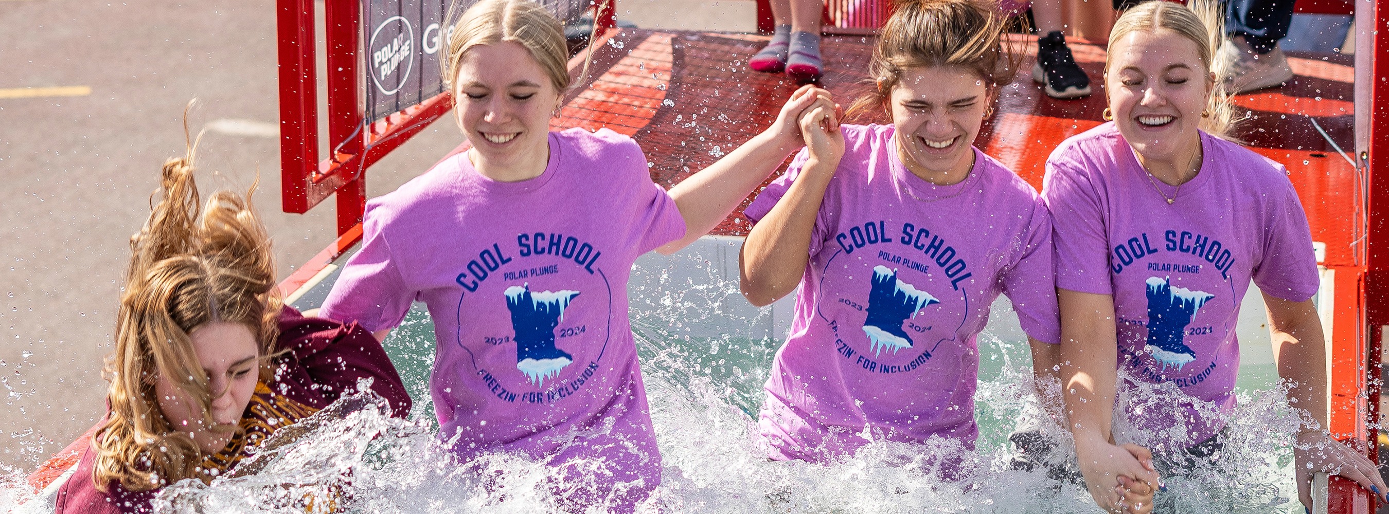 4 Students jumping into the water at a polar plunge event
