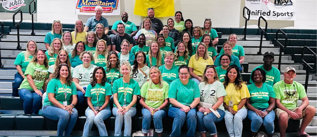 JMC staff smiling and sitting on bleachers