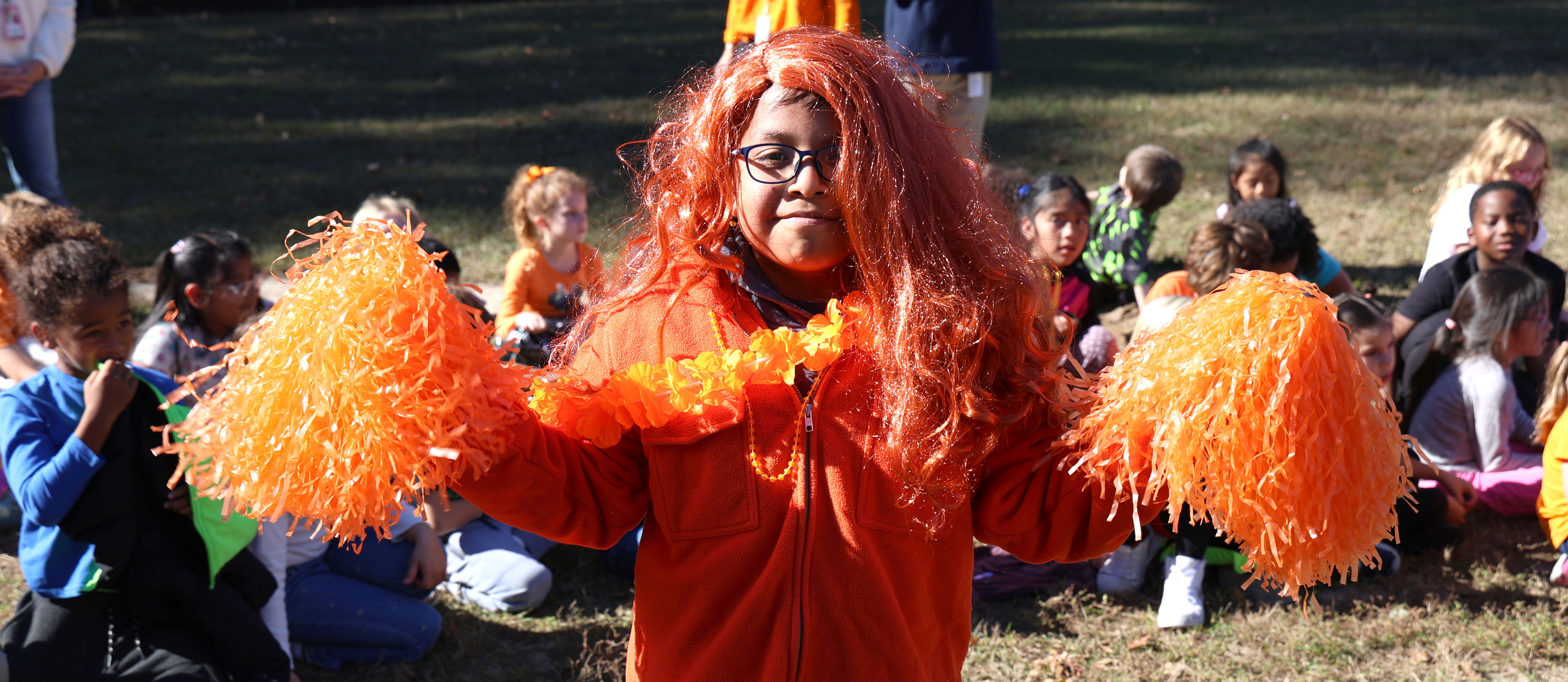 Student wearing orange holding pom-poms