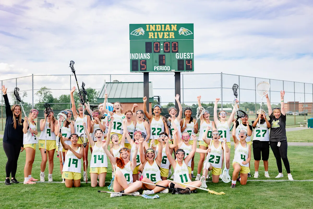 team smiling in front of score board
