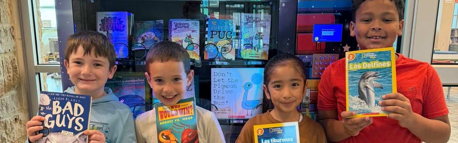students holding books infront of their book vending machine