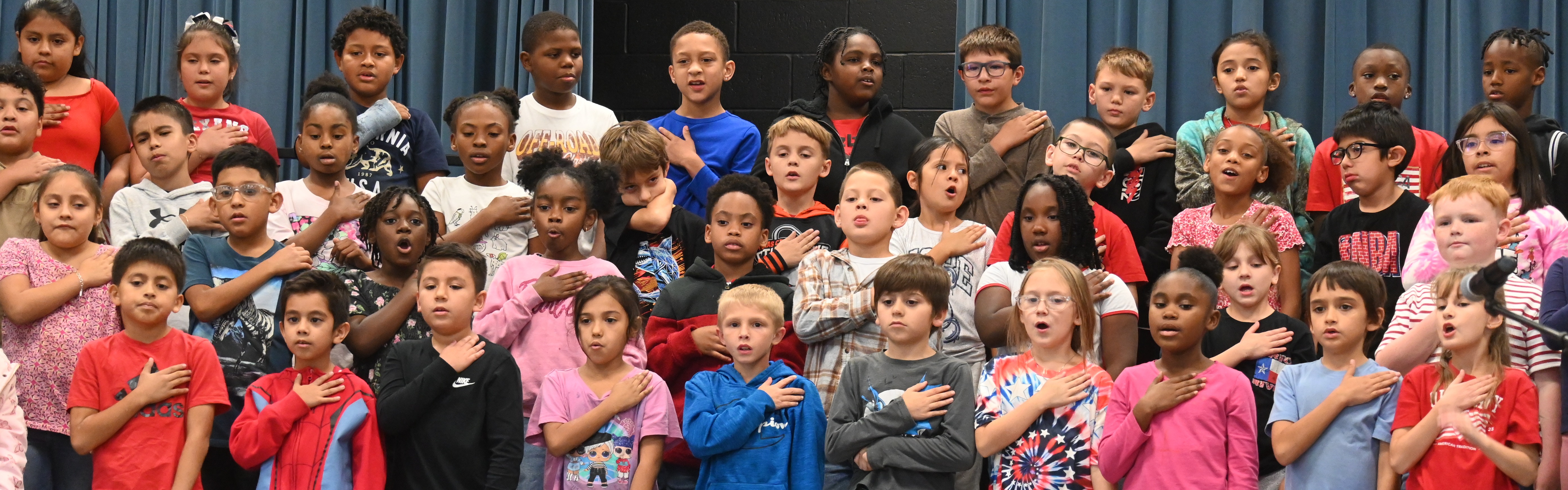 students with hands over heart singing at a patriotic program
