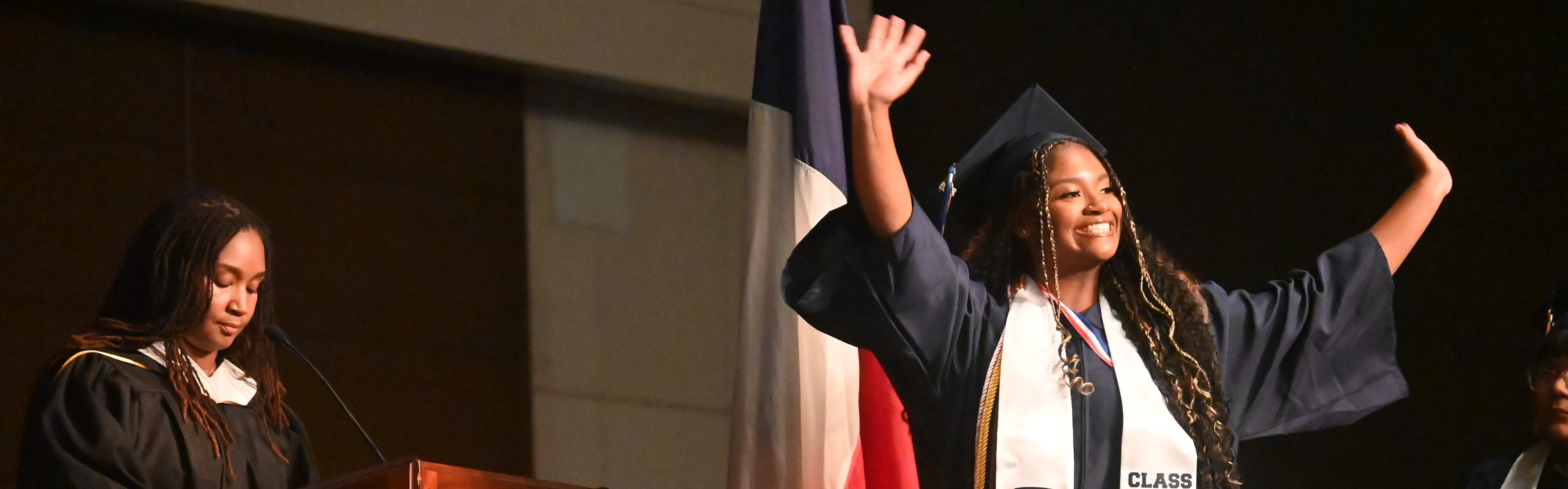 Graduate lifts arms in celebration at the graduation ceremony