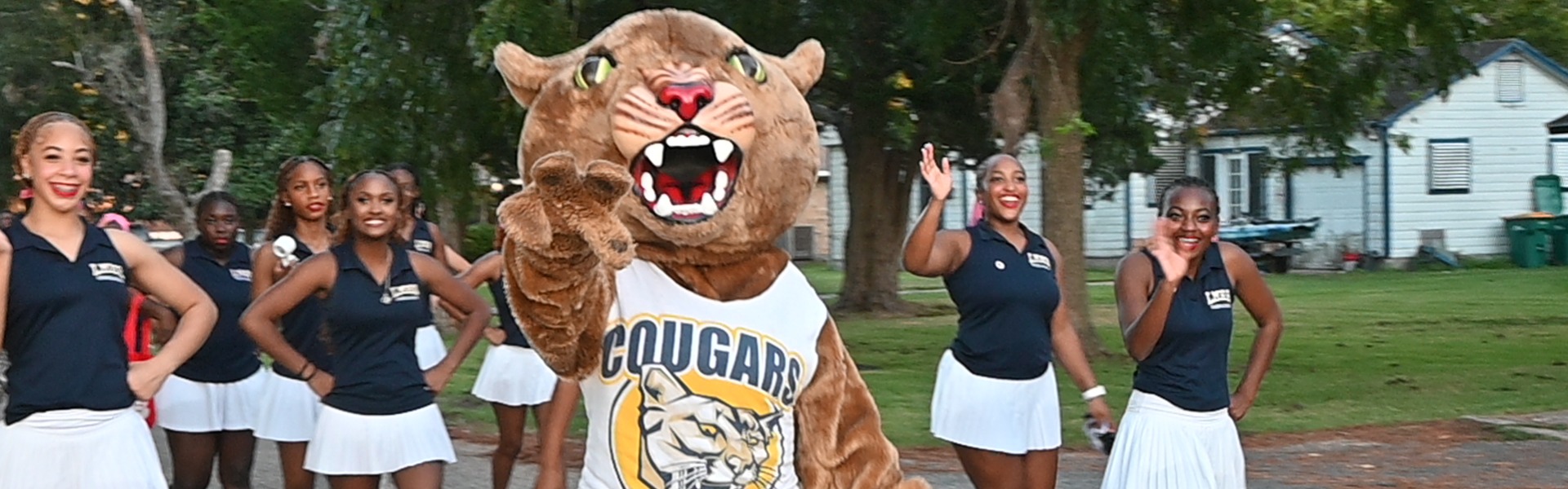 La Marque Cougar mascot waves and is surrounded by cheerleaders as they walk in the 2026 Homecoming Parade
