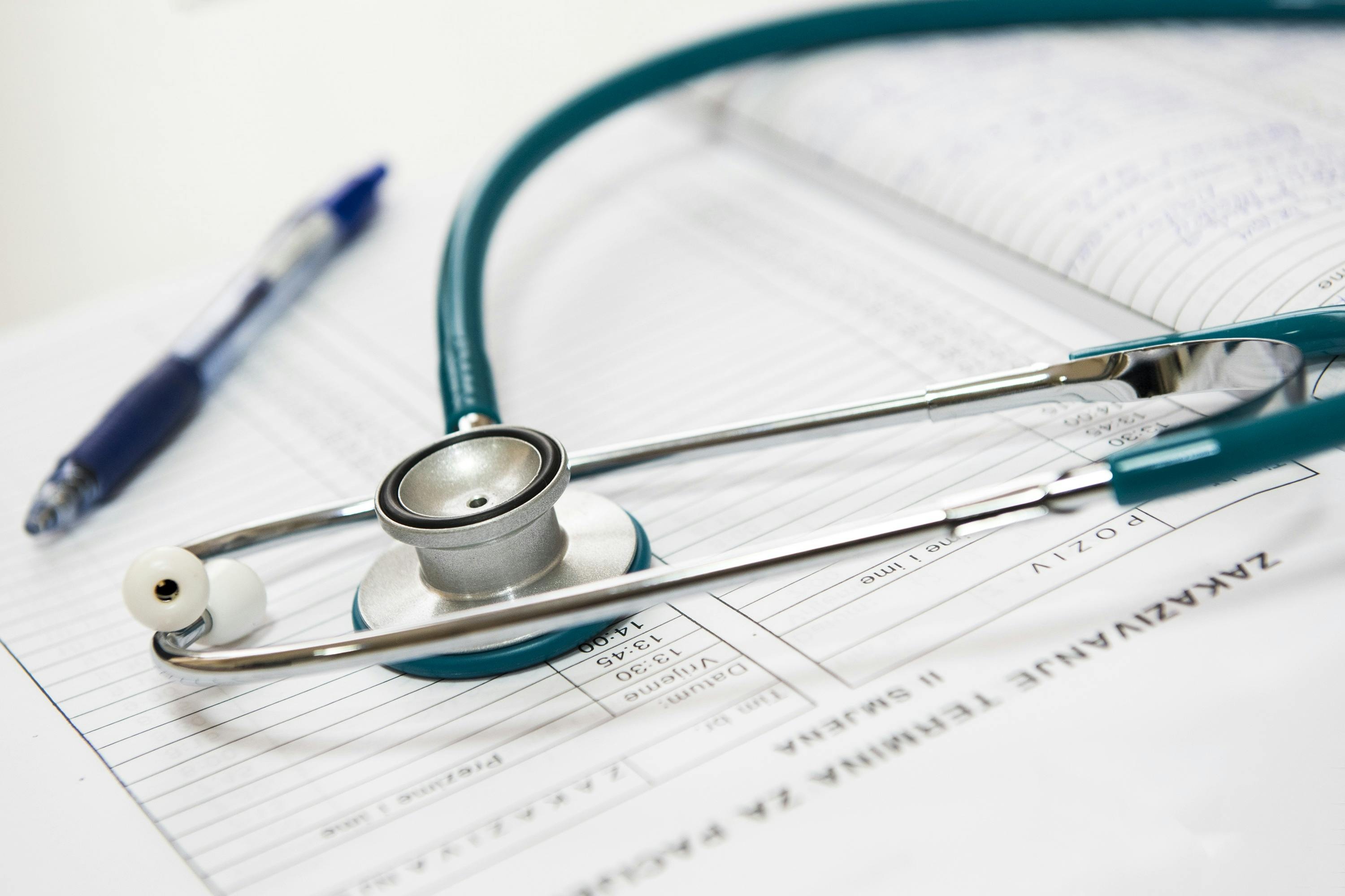 Stethoscope and pen laying on top of medical paperwork