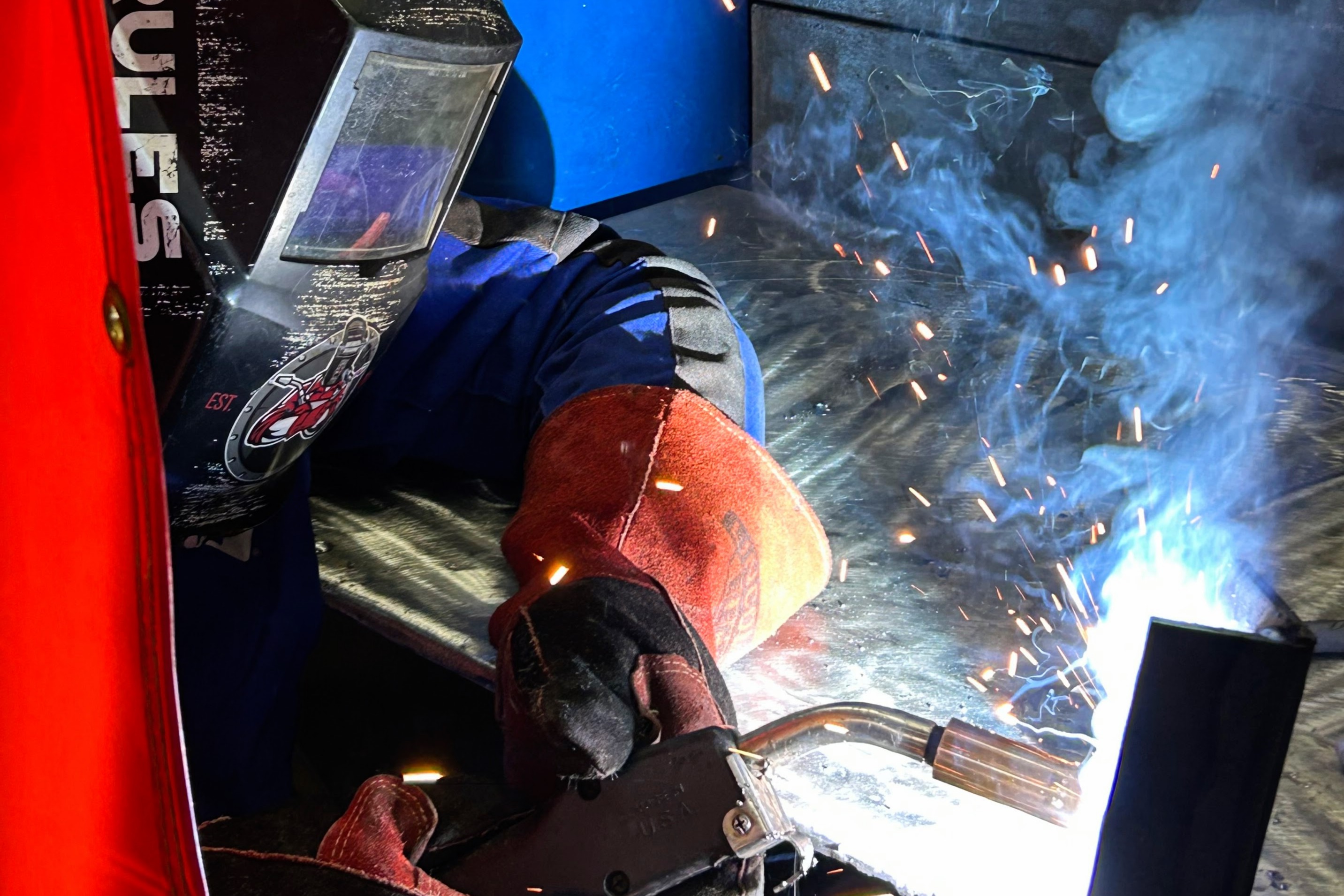 Welding student working with torch, with gloves and helmet