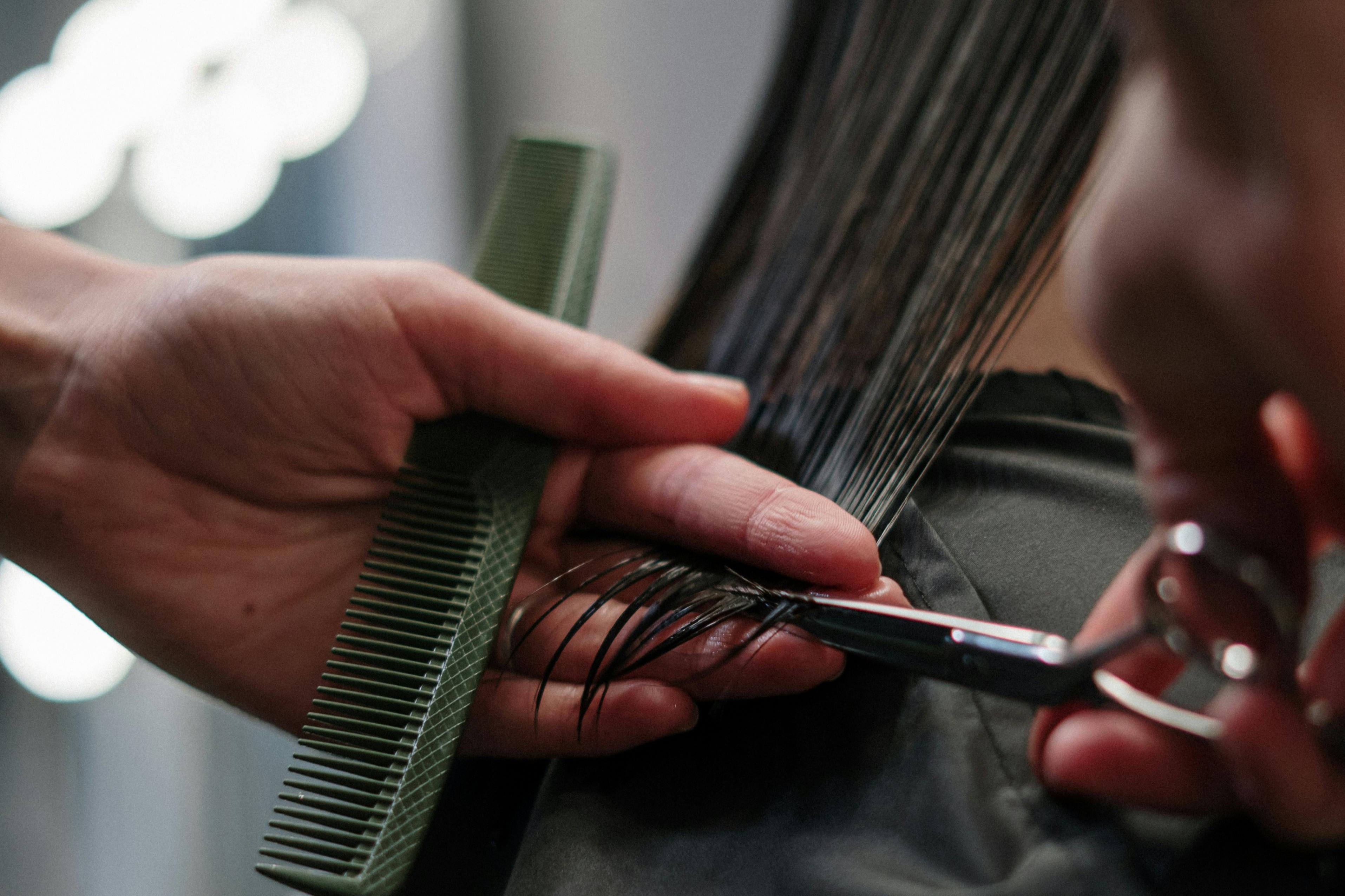 Close up of student cutting hair, with comb and scissors