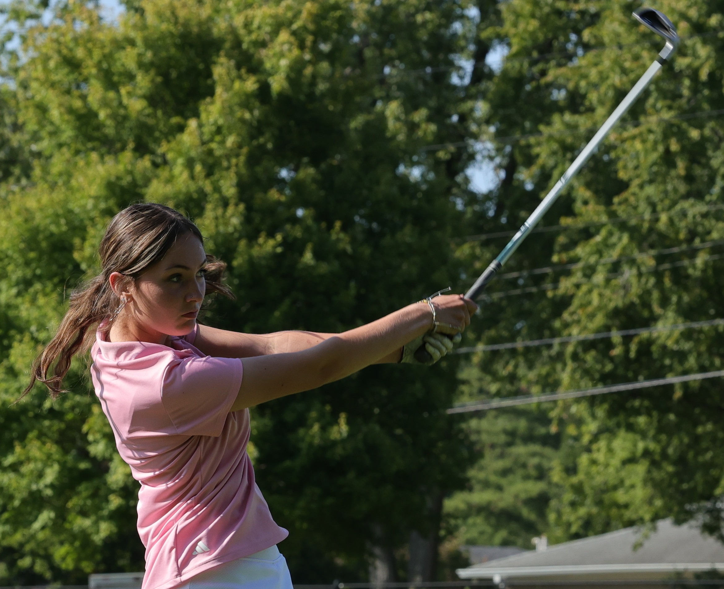 Student swinging a golf club at the golf course