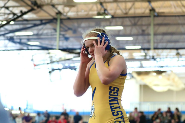 female swimmer adjusting swim goggles with a yellow swimsuit 