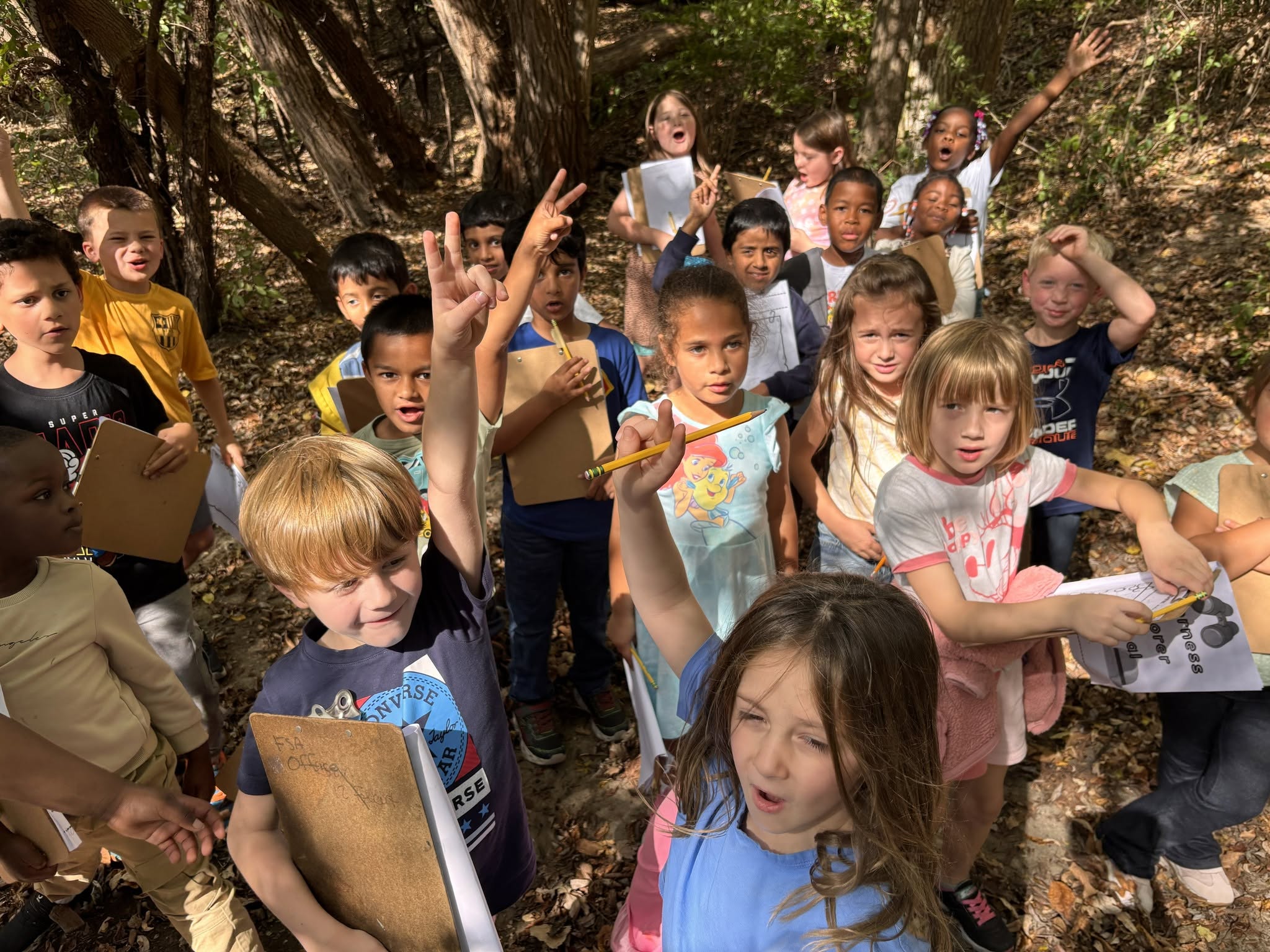 A group of students standing outside raising their hands to answer a question
