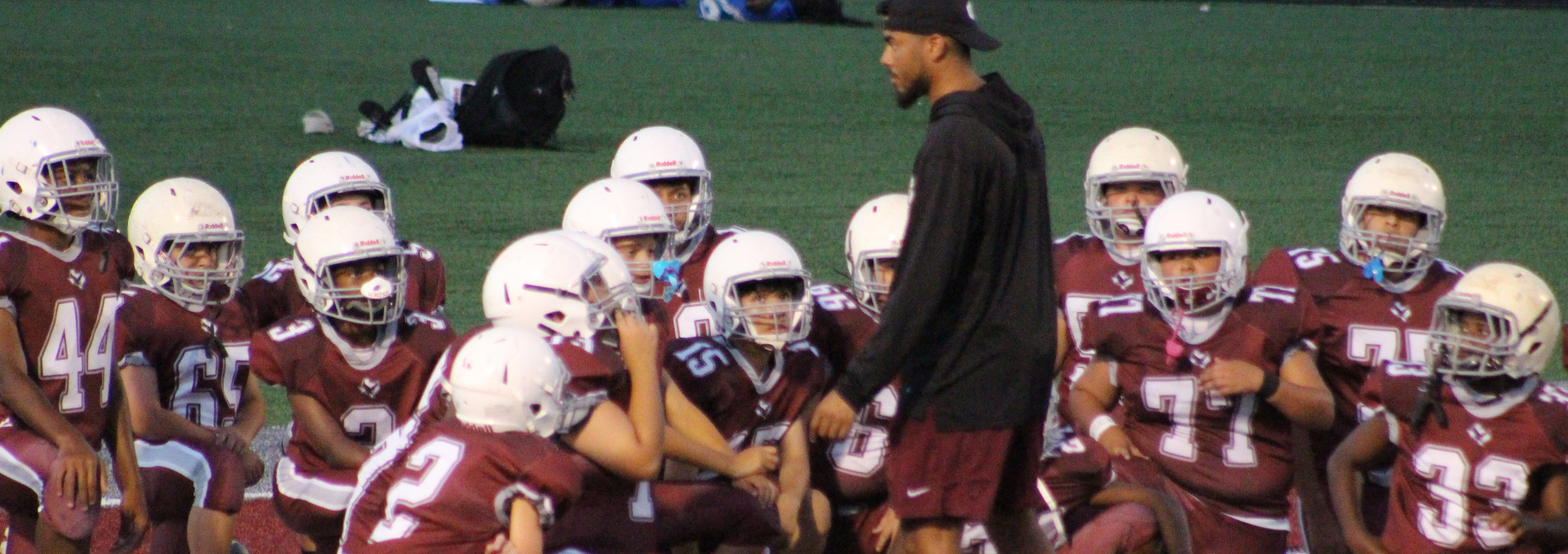 Picture with a coach and football players in uniform.
