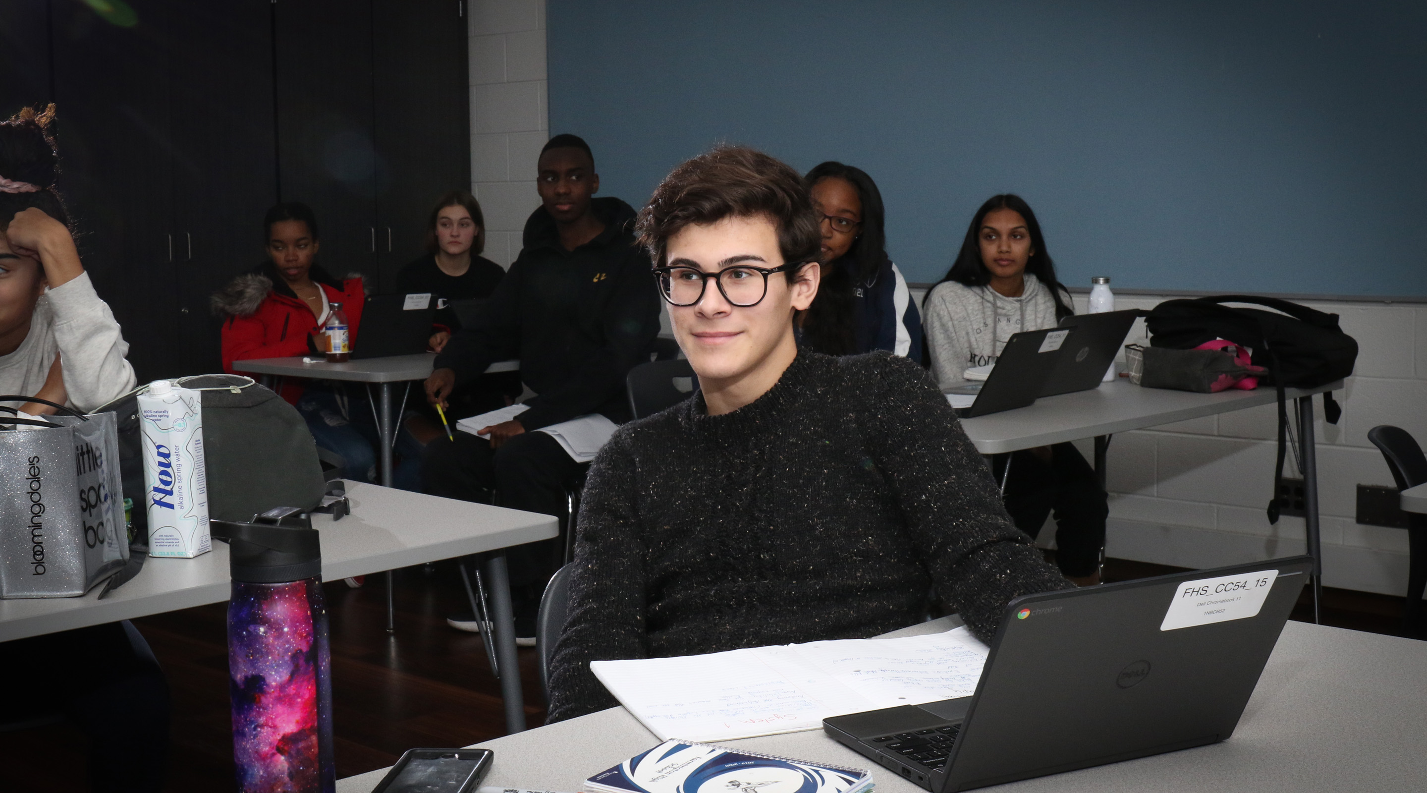 High school male student sitting in class looks off to his right.