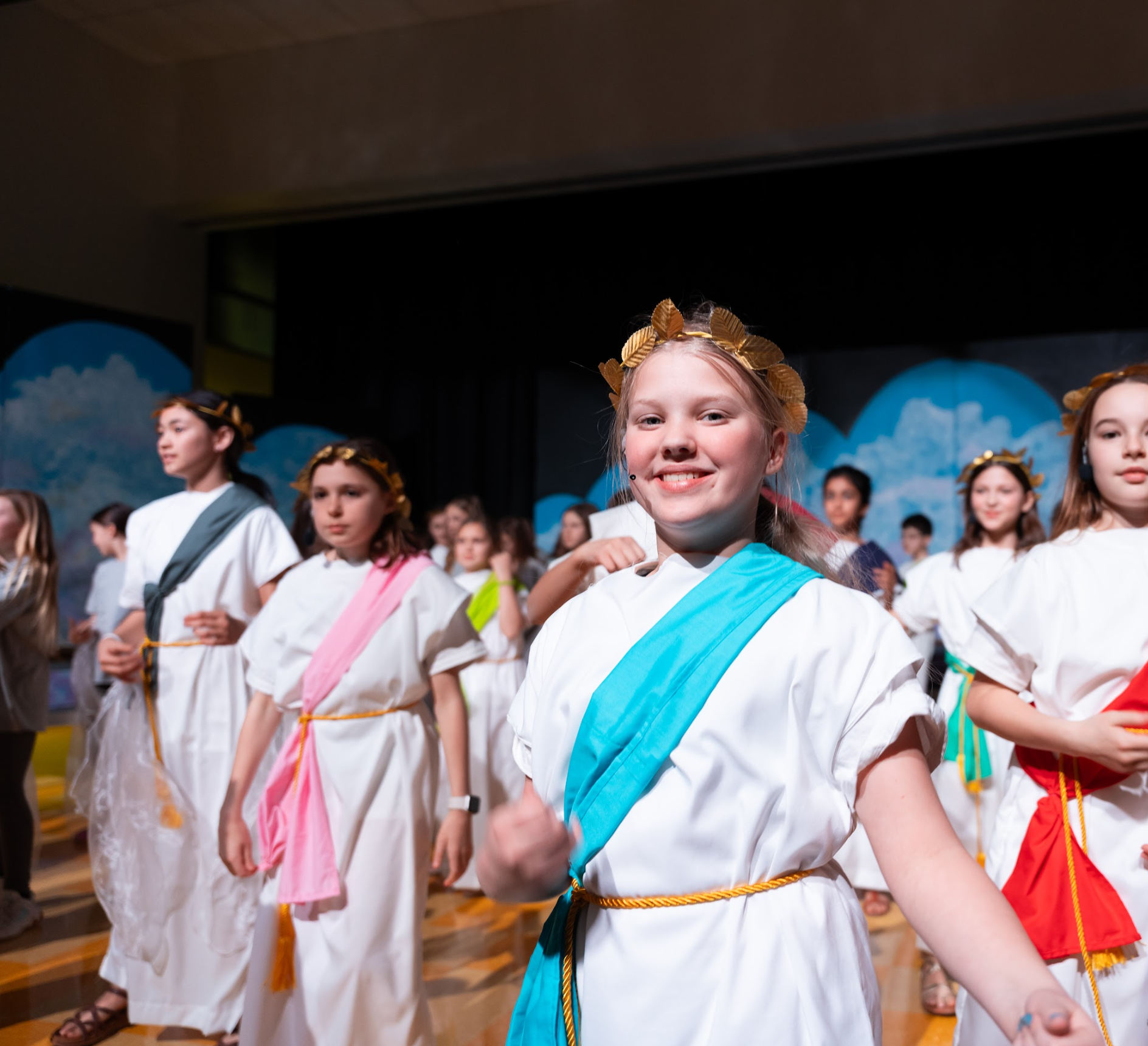 This image shows 5th grade students dressed in Greek Olympian costumes as they perform their spring 2026 musical.  