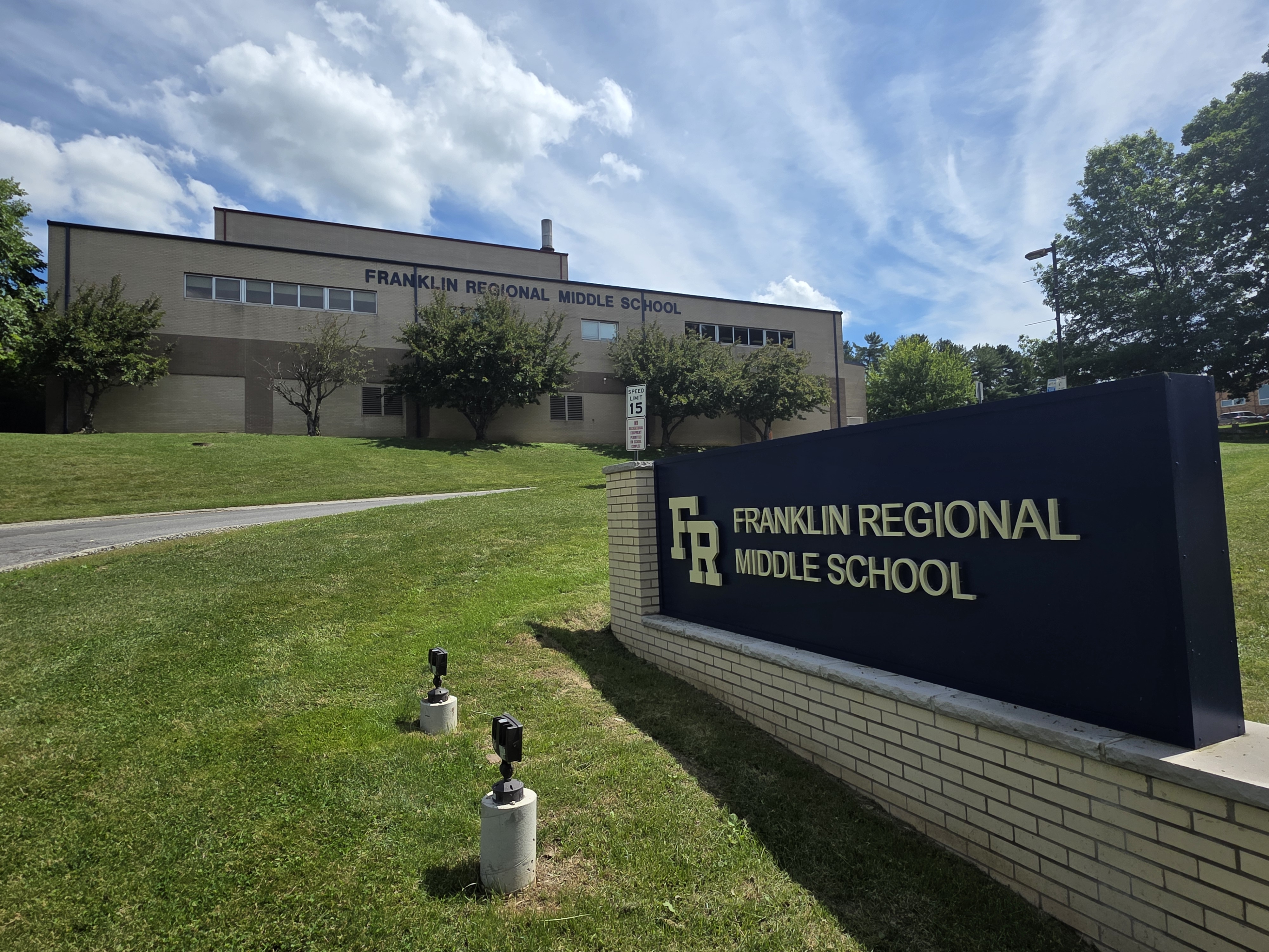 A large school building is in the background, with a sign for Franklin Regional Middle School in the foreground.