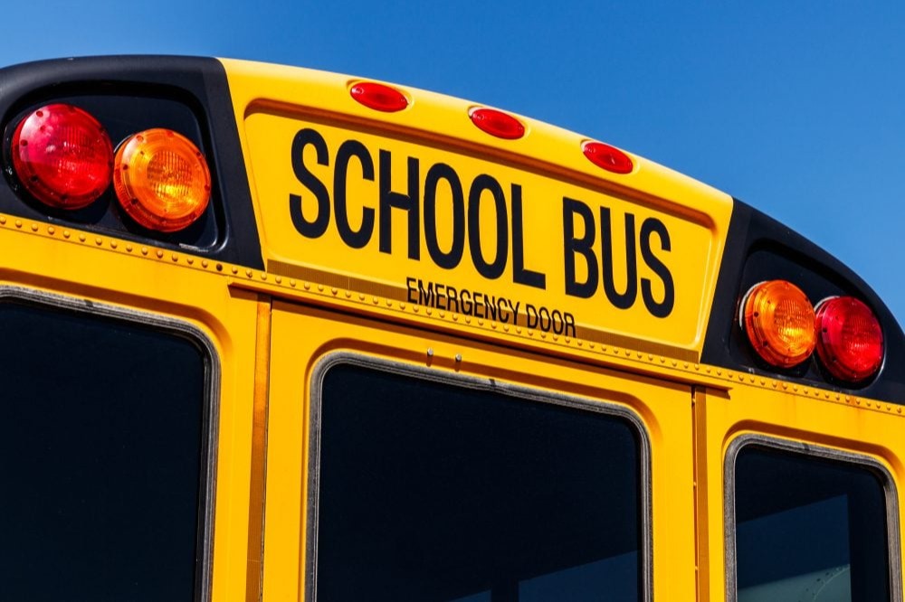 "Rear section of a yellow school bus showing the emergency exit door and warning lights."