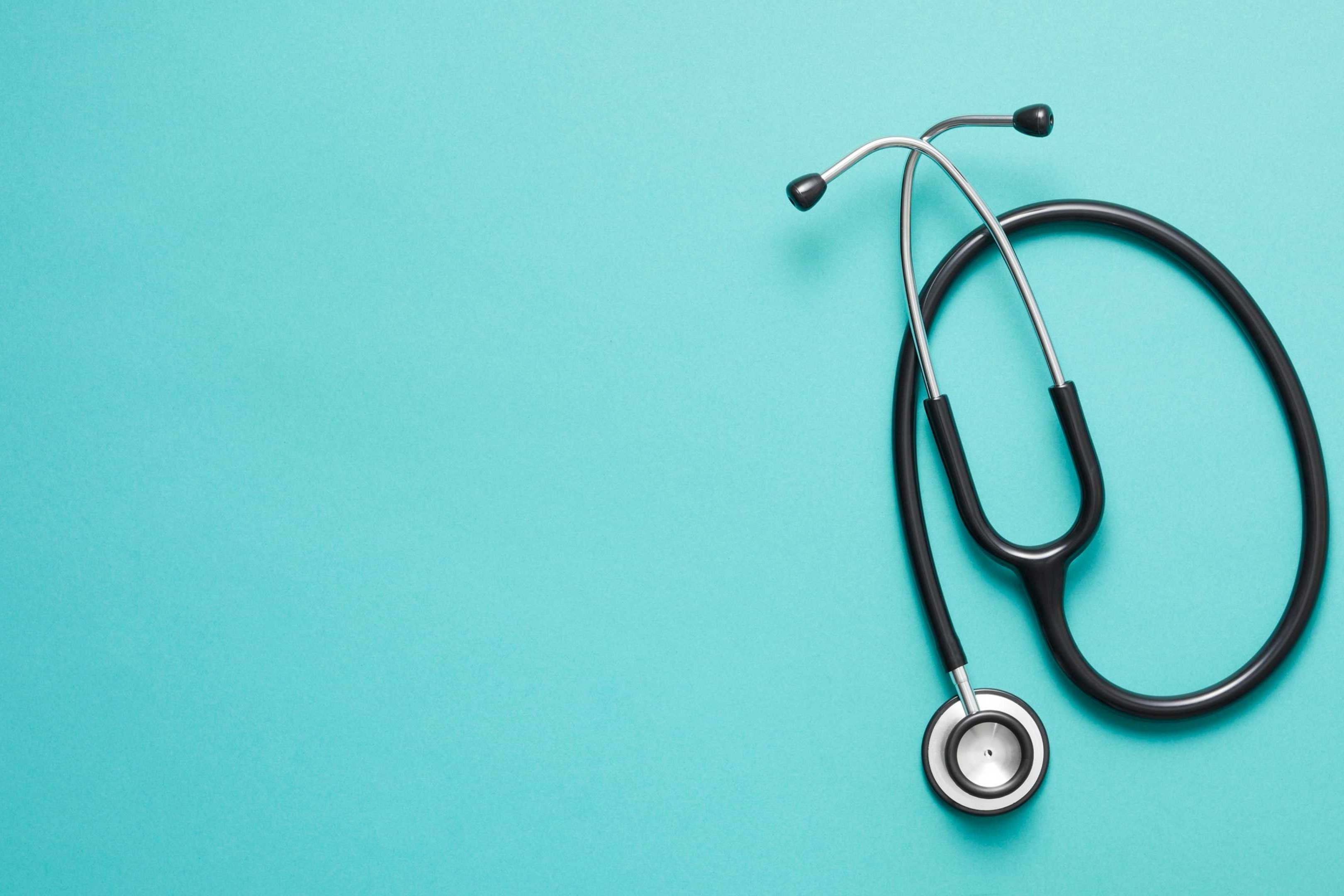 A stethoscope with a silver bell and black tubing lies on a blue background.