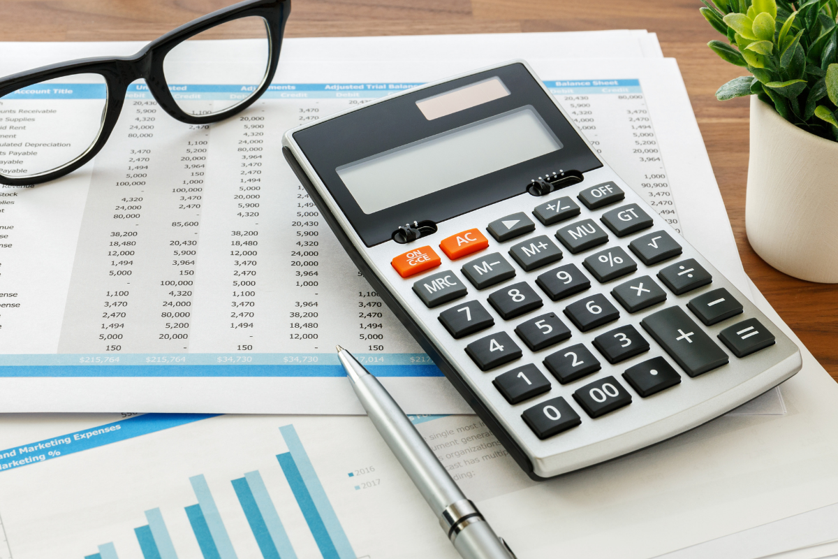 desk with eyeglasses, calculator, pen, and plant