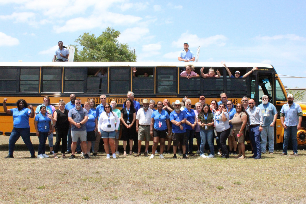 group of transportation staff posing in front of a school bus