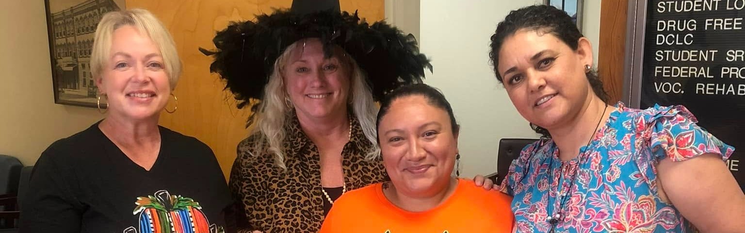 staff wearing Halloween costumes and posing for a picture