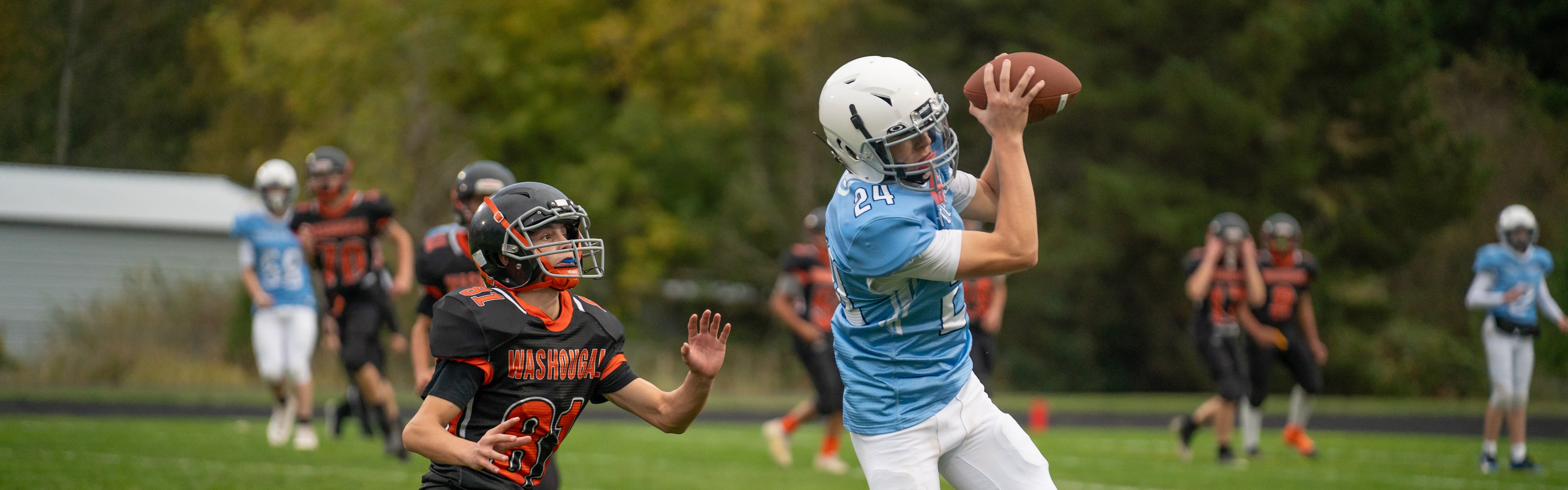 Two students playing football on field