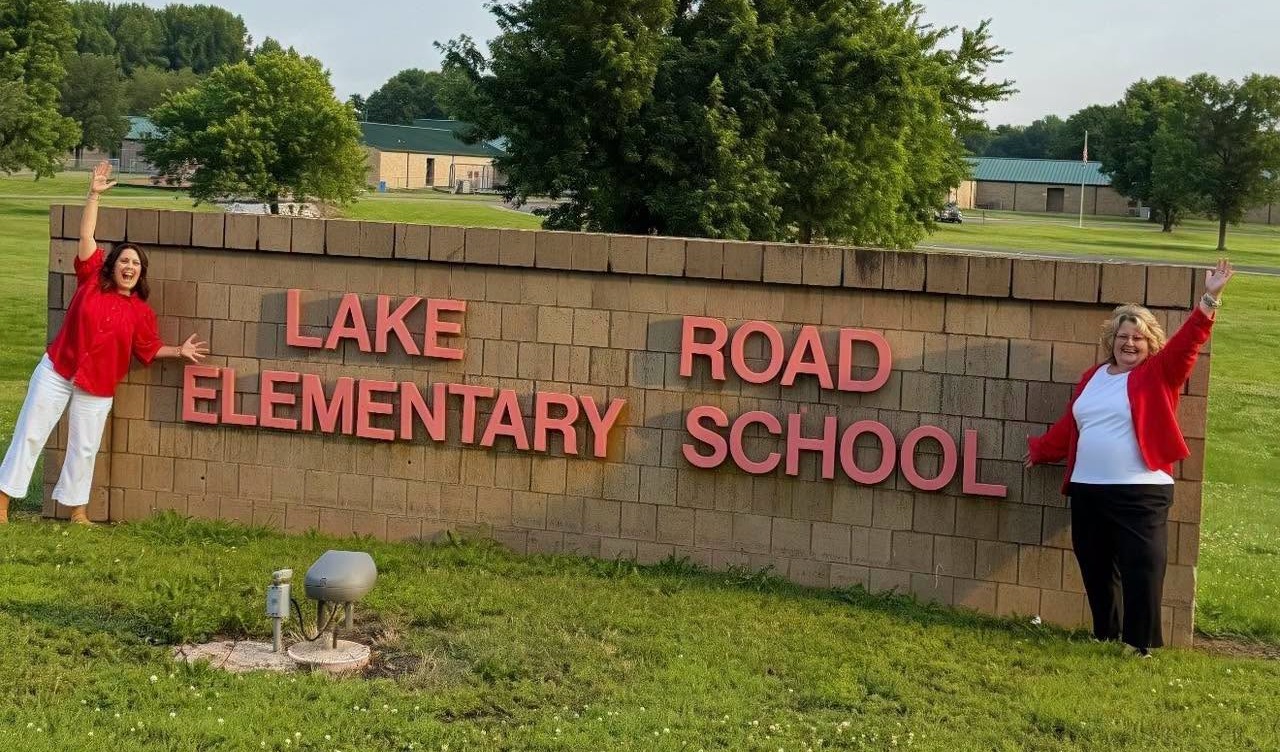 Two administrators in front the Lake Road sign.