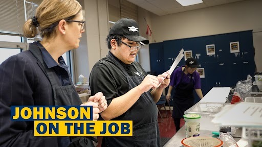 Two individuals in a kitchen; one man holds a piece of paper while the other looks at it. Text reads "Johnson on the Job".