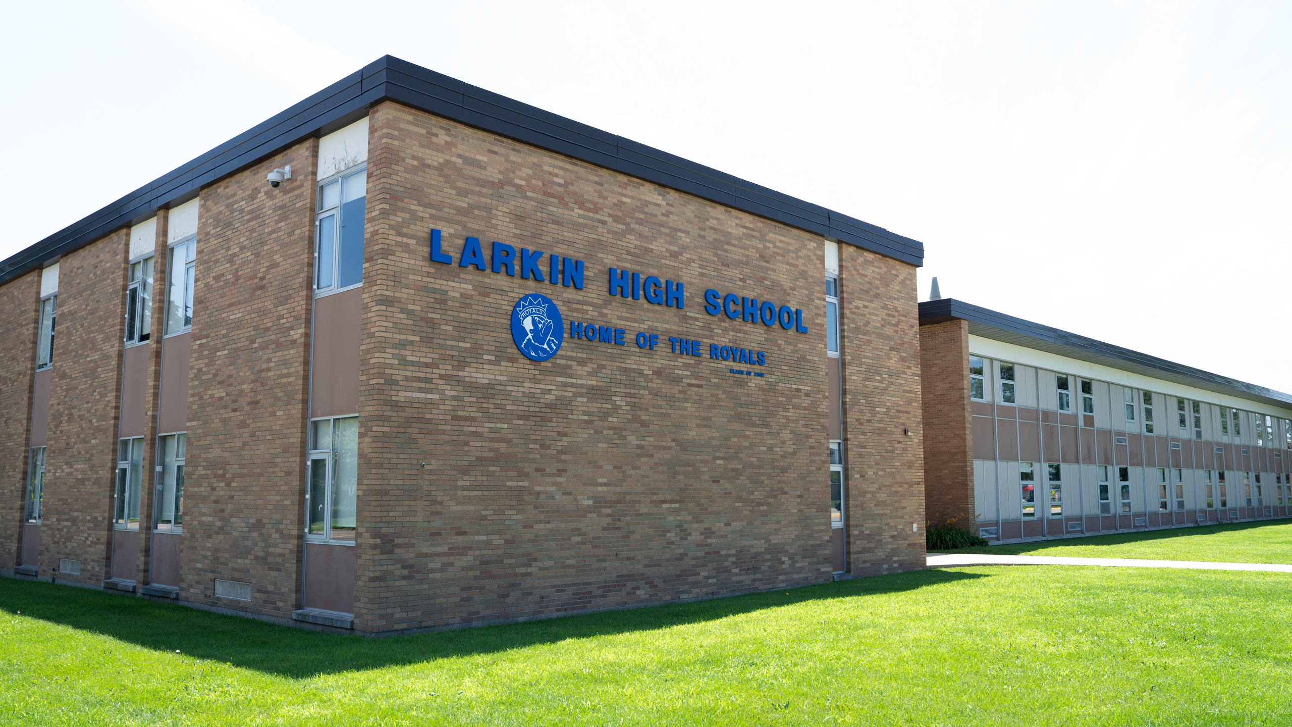 A school building with a brick facade. Text on the wall reads "LARKIN HIGH SCHOOL" and "HOUSE OF THE WORLD."