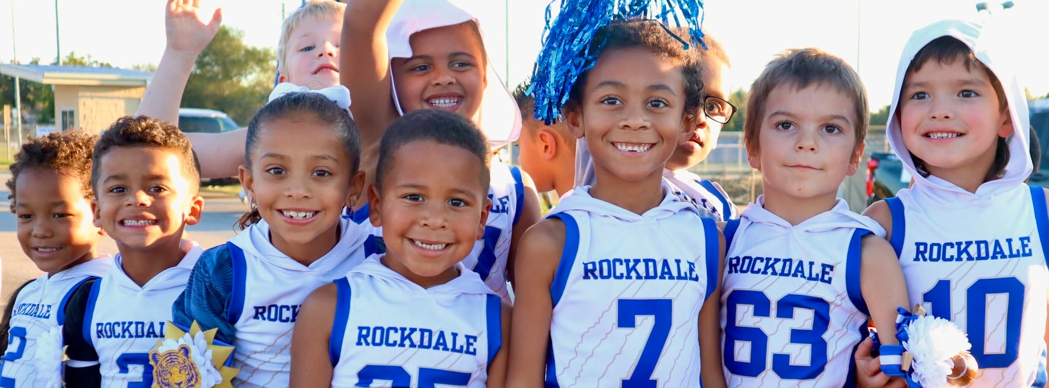 Group of students standing together in football jerseys smiling.