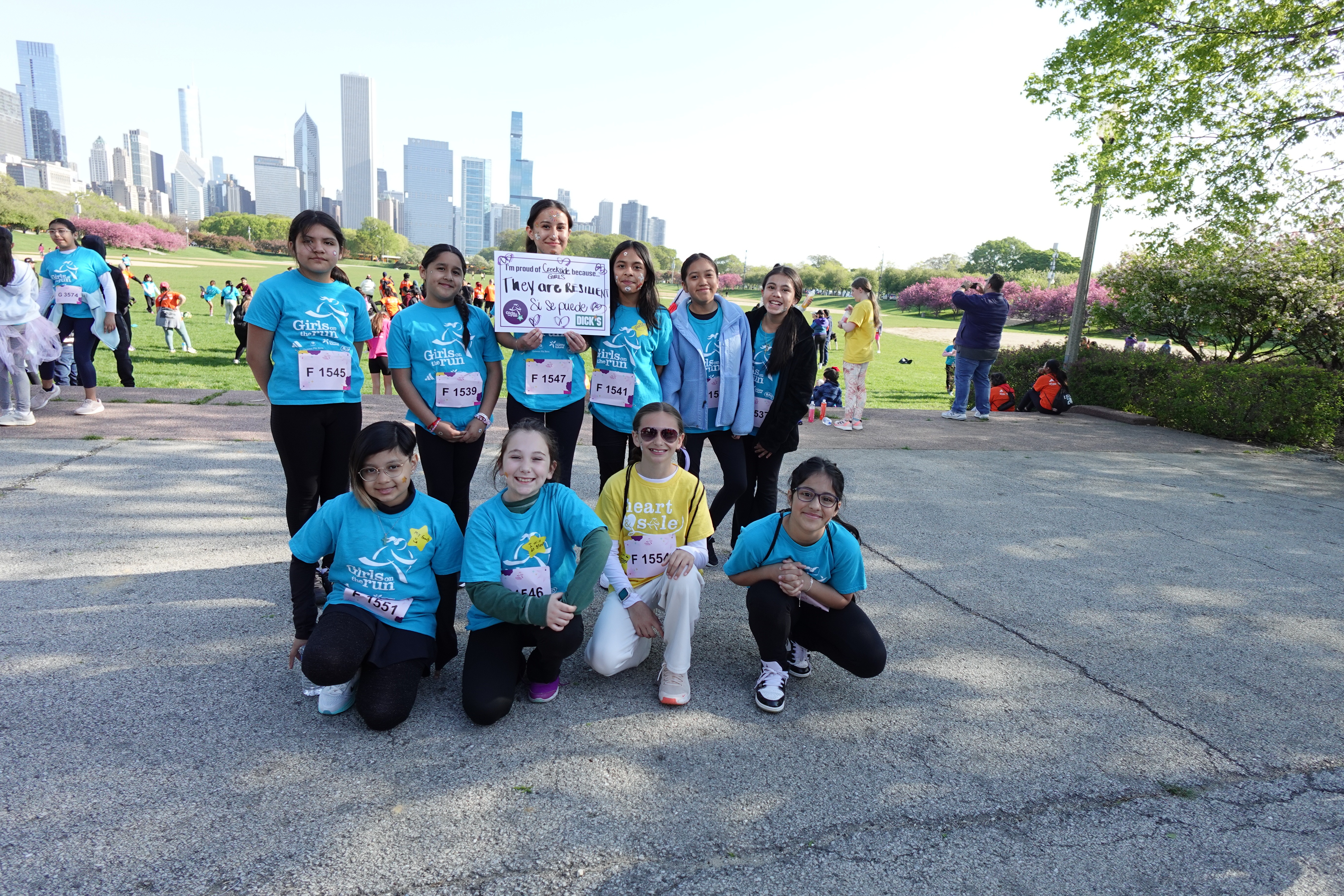 Group of children in matching shirts, posing for a photo, with a city skyline in the background.