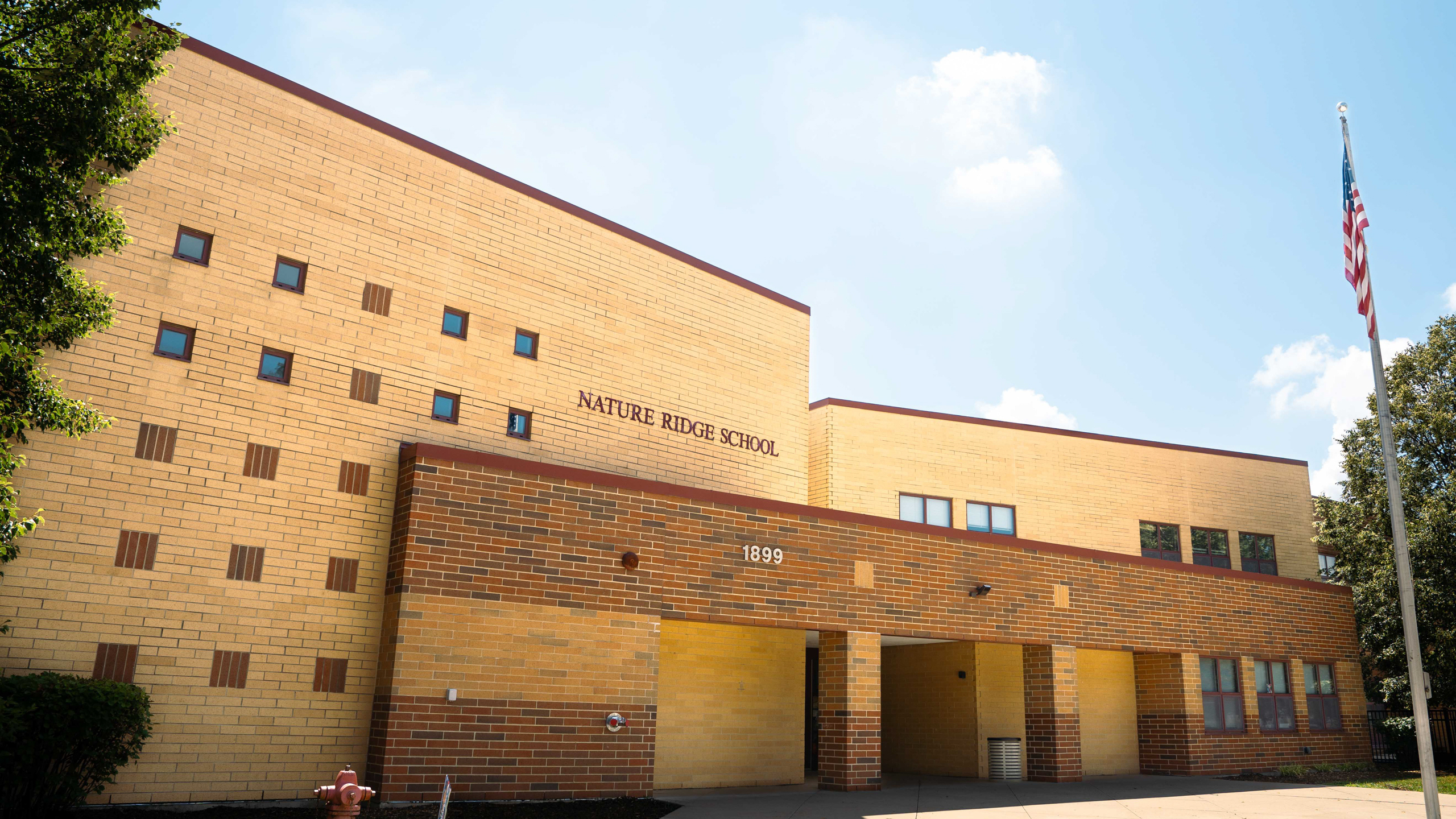A building with a brick facade, multiple windows, and an American flag in front.