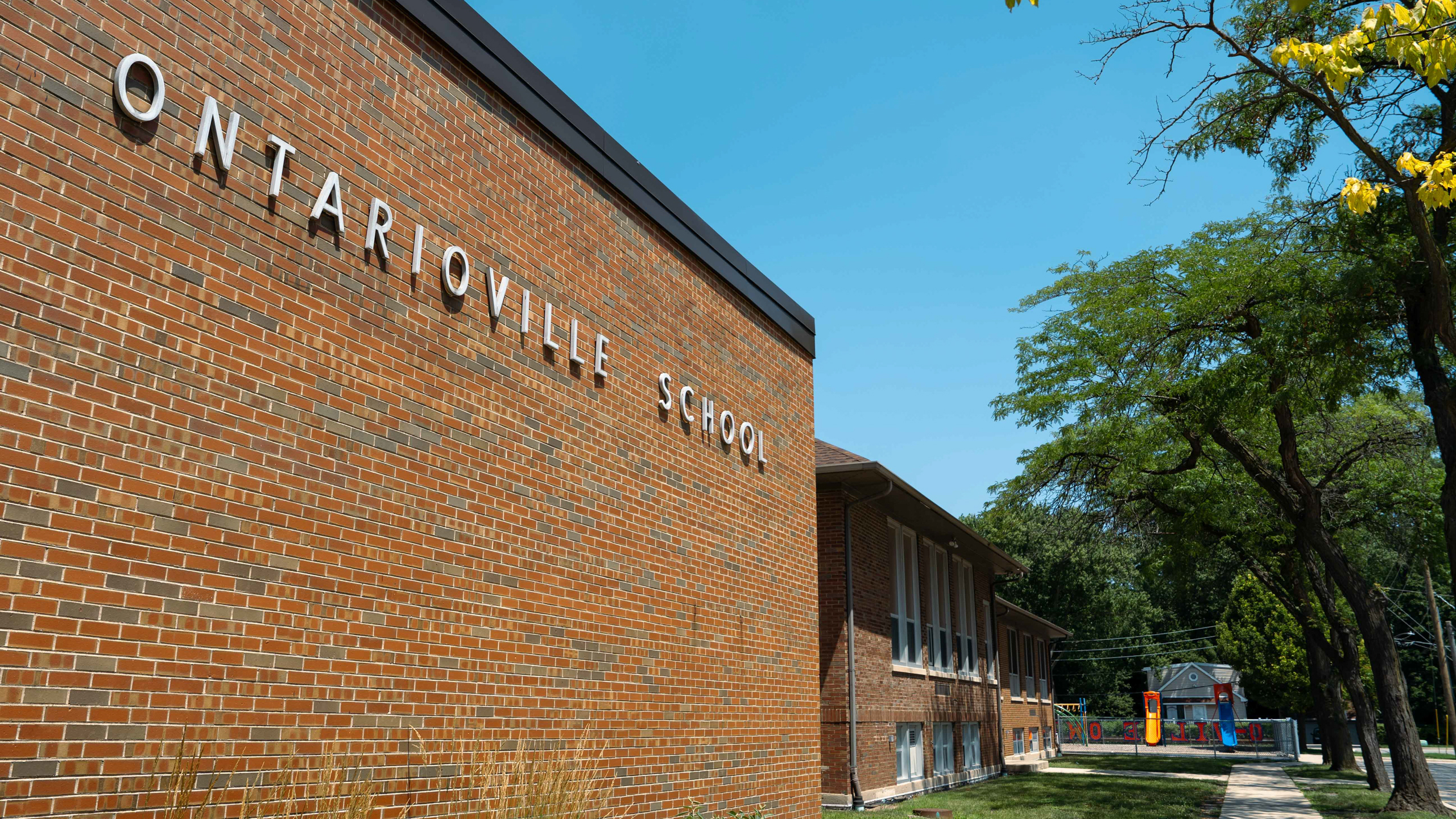 A brick building reads "ONTARIOVILLE SCHOOL" with windows and trees in the background.