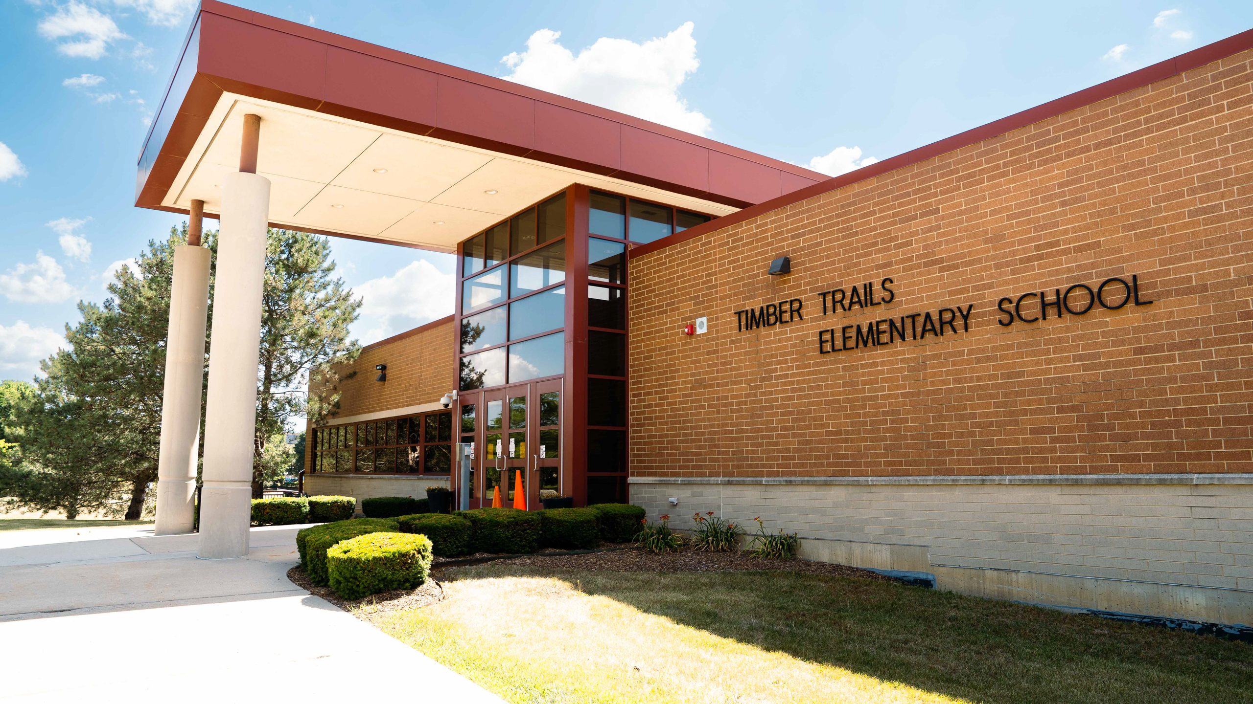 Exterior of Timber Trails Elementary School with brick walls, glass windows, and a red roof.