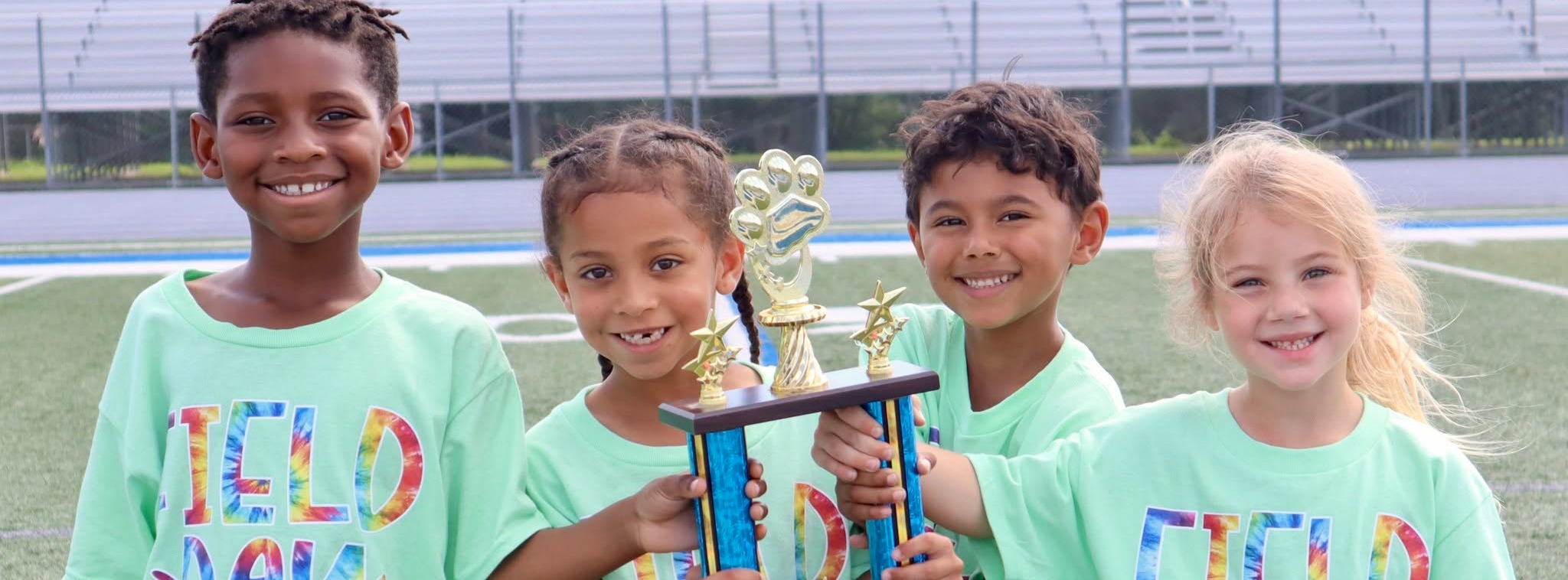 Group of children standing together smiling holding a trophy
