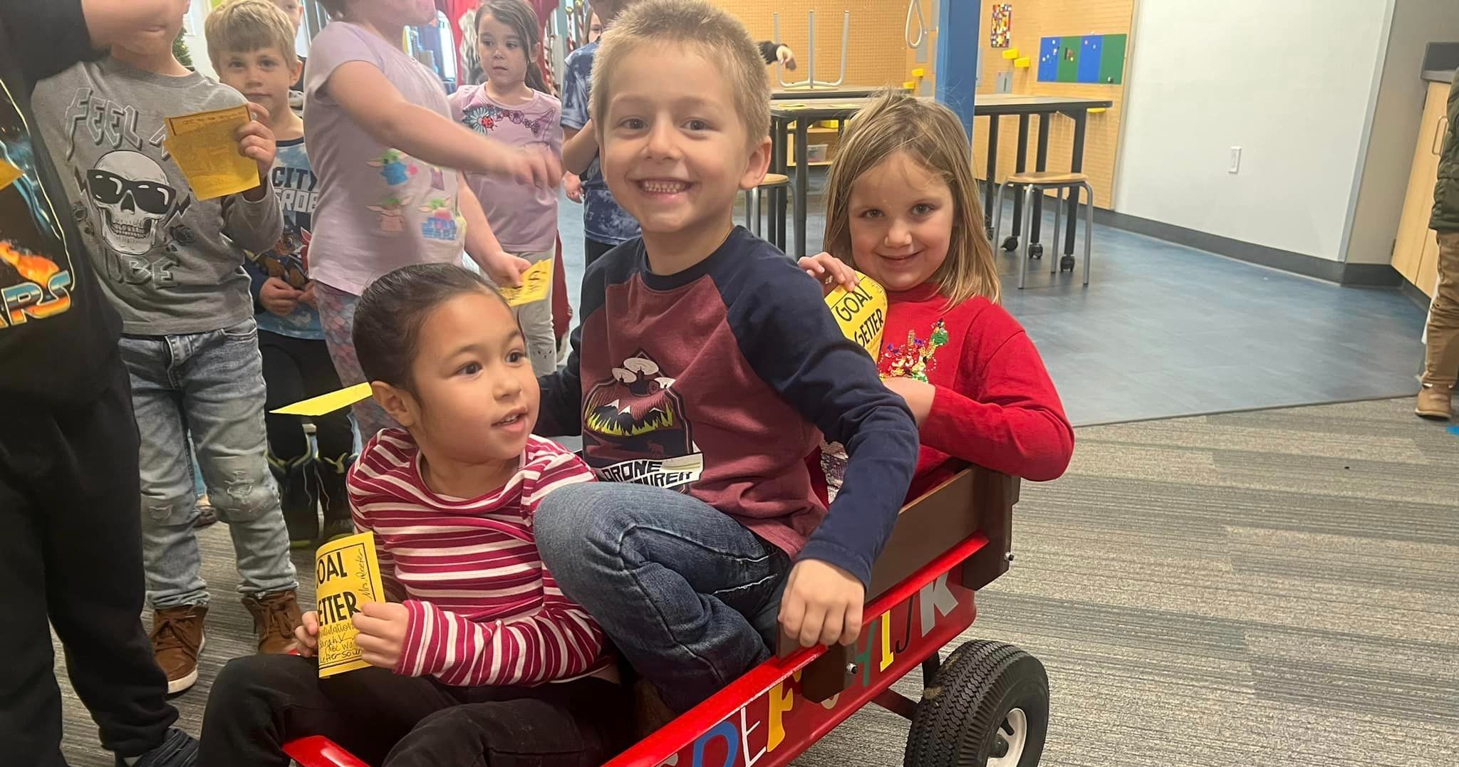 three children sitting in a wagon