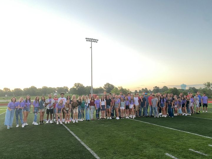 Class of 2022 standing on football field at sunrise