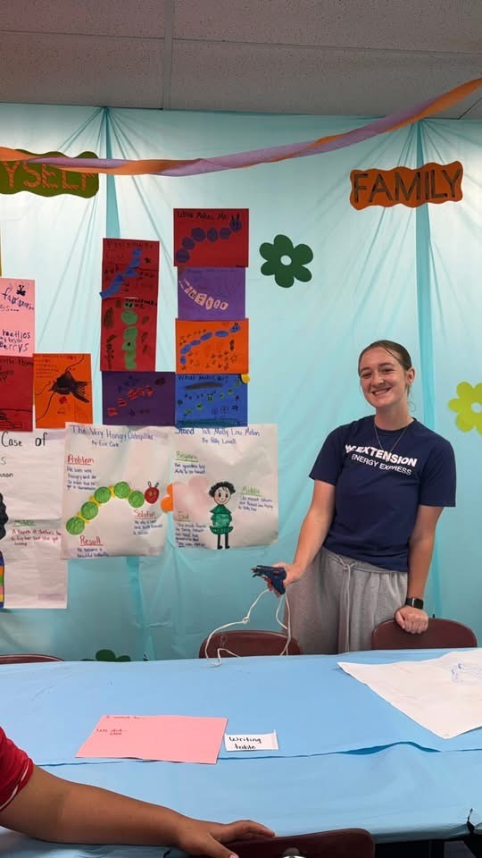 Student in blue shirt with blue background and had art display