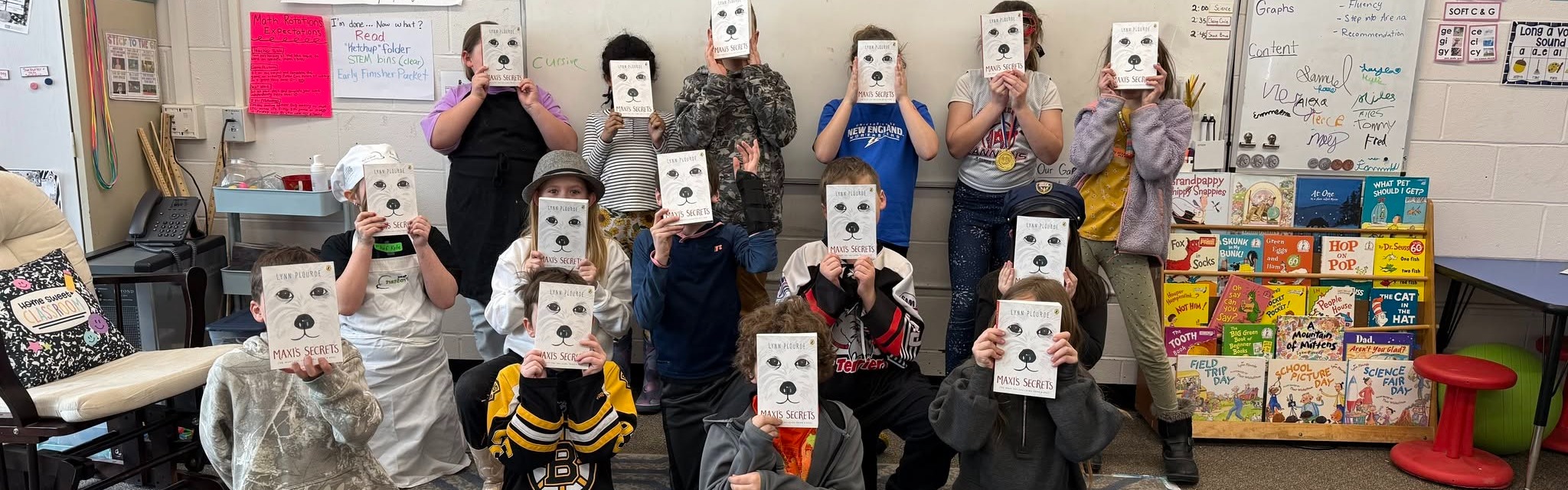 class of students holding a book in front of their faces