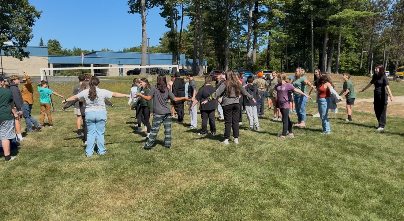 students in a field with their arms out