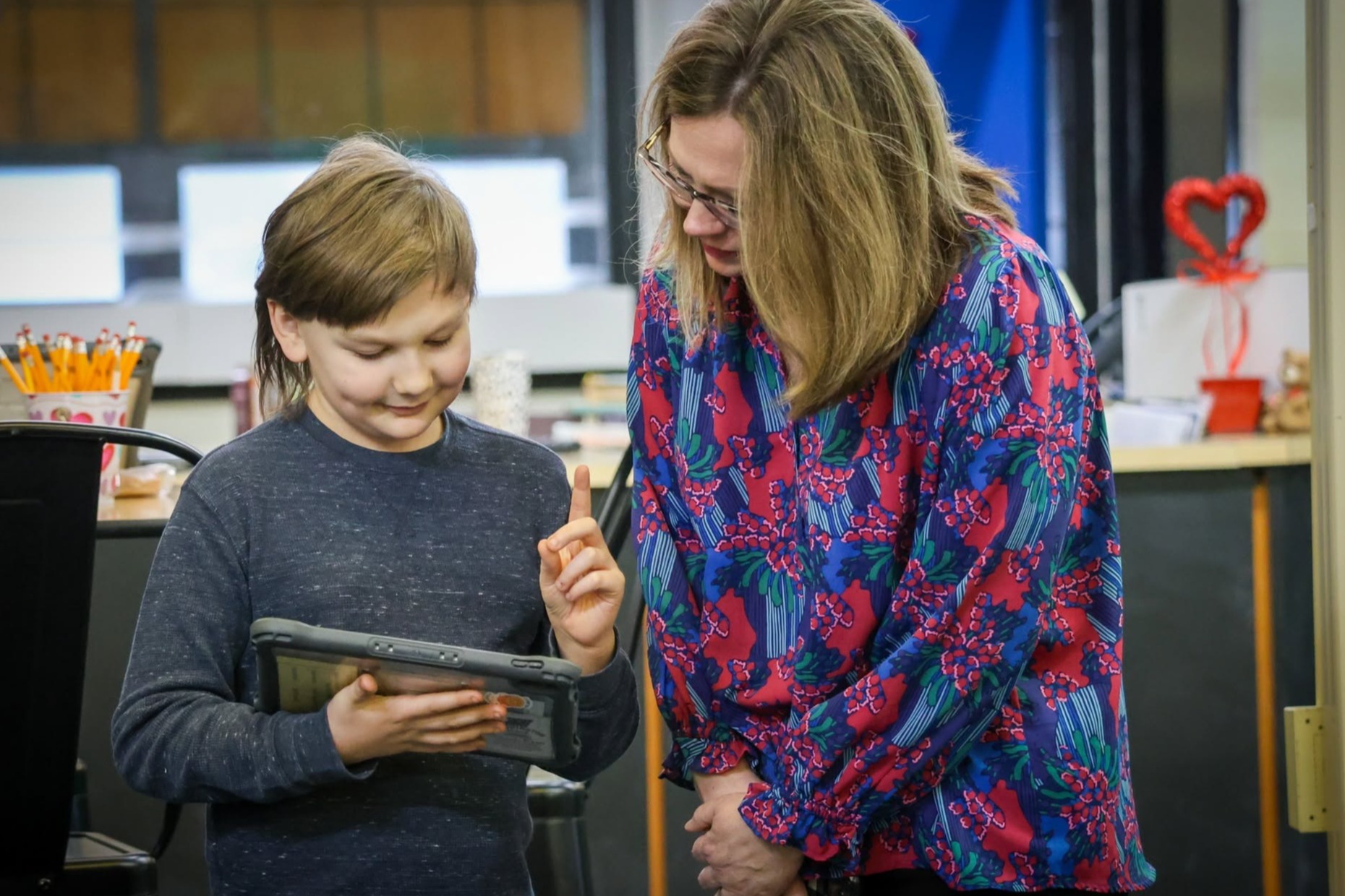 A teacher helps a student with their iPad
